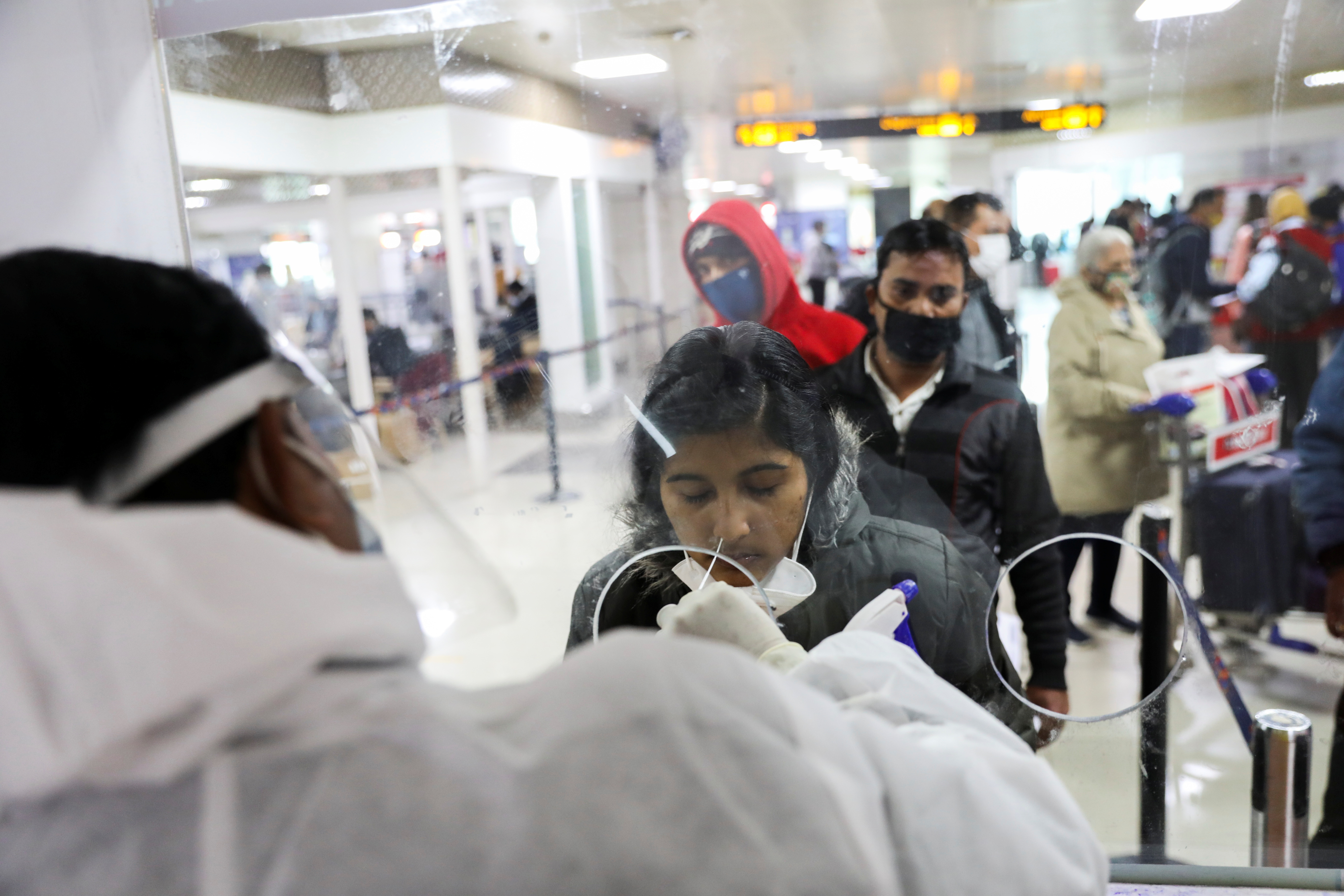 A healthcare worker collects a coronavirus disease (COVID-19) test swab sample from a woman at the Indira Gandhi International Airport in New Delhi, India, December 3, 2021. REUTERS/Anushree Fadnavis