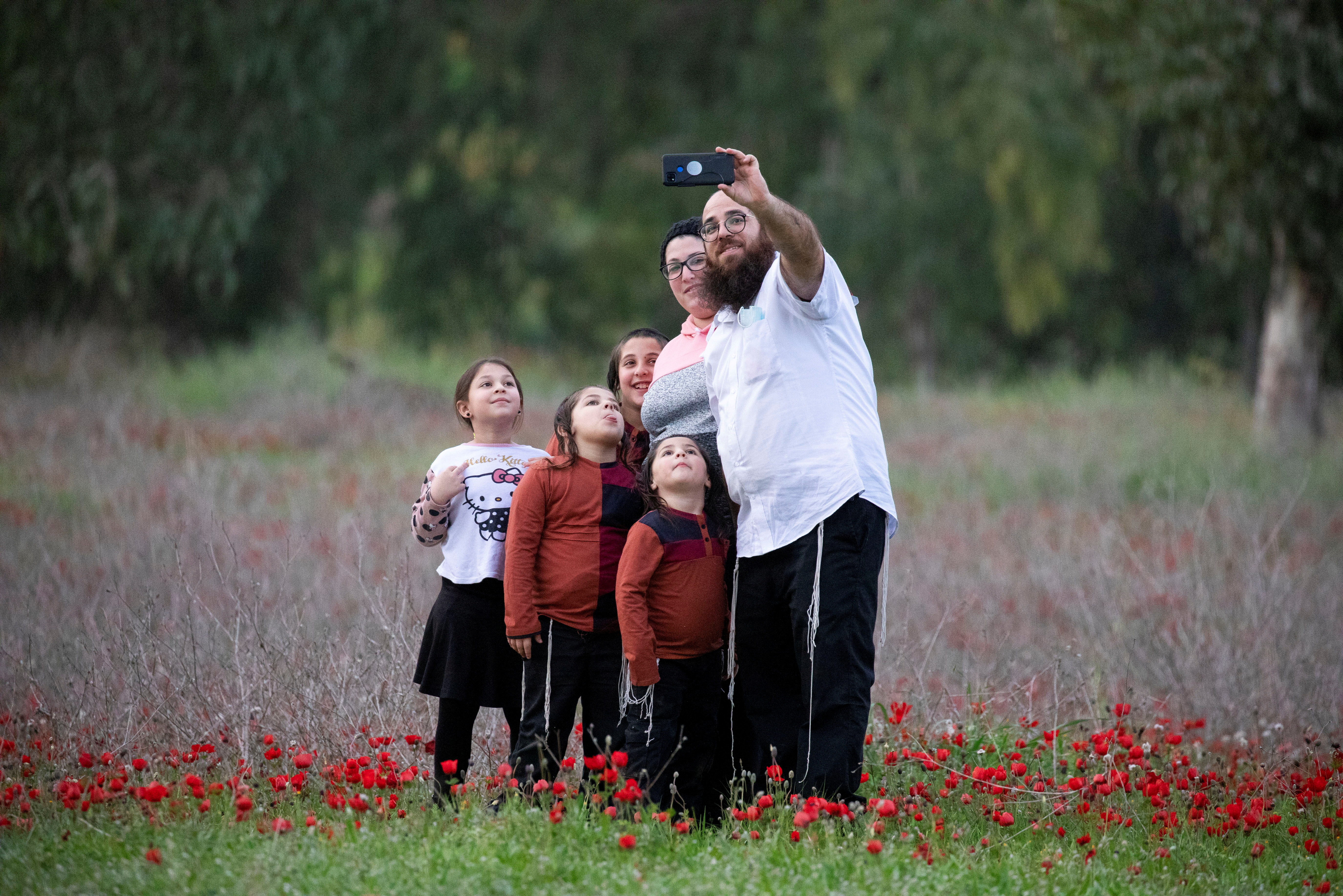 A family takes a selfie in an anemones field near Kibbutz Beeri in southern Israel