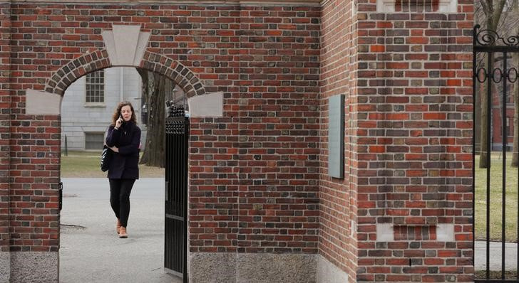 A woman walks through a gate to the Yard at Harvard University in Cambridge