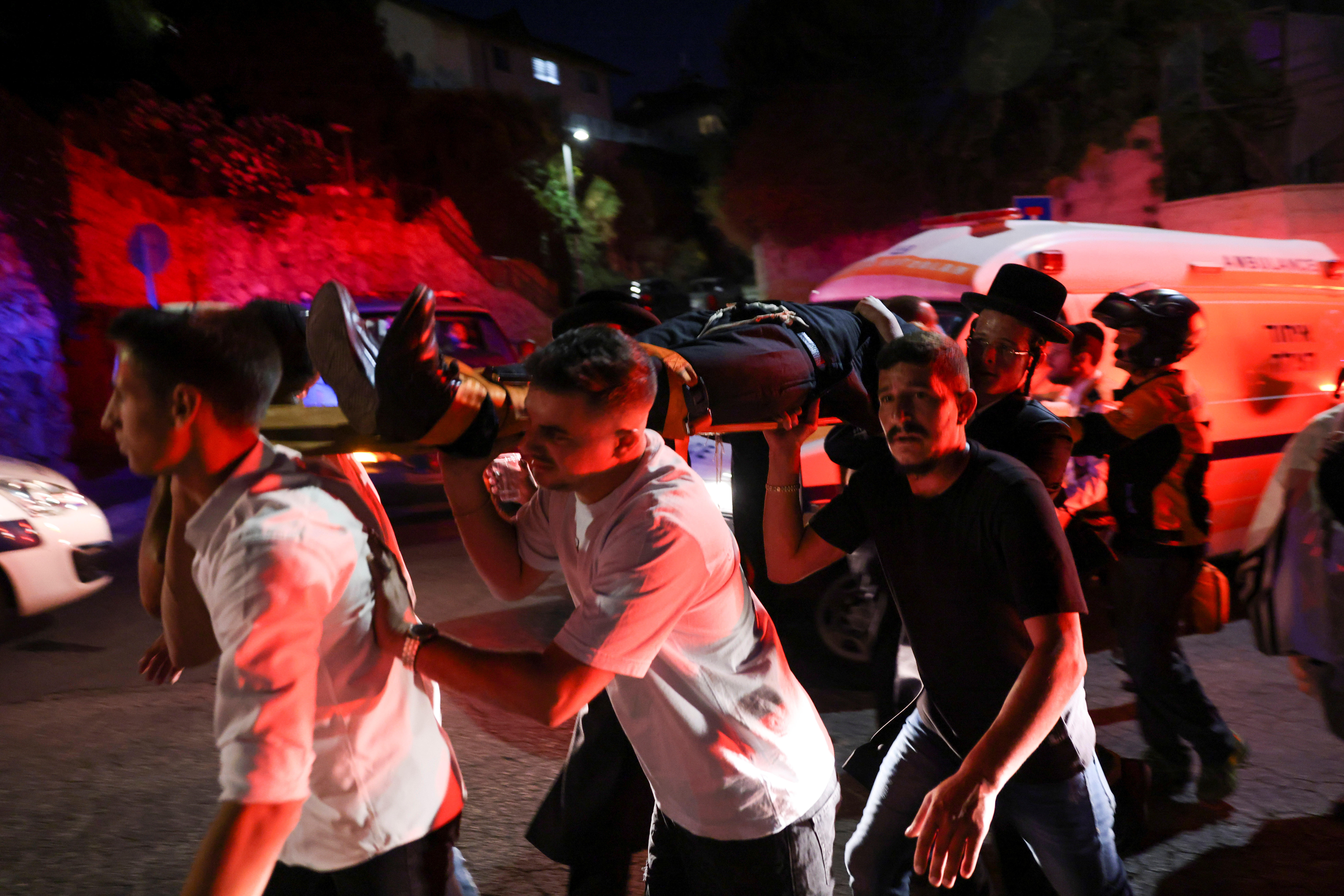 Jewish worshippers and rescue workers carry injured people outside a synagogue where a grandstand collapsed during a religious celebration in Givat Zeev, in the occupied West Bank, May 16, 2021. REUTERS/Ronen Zvulun