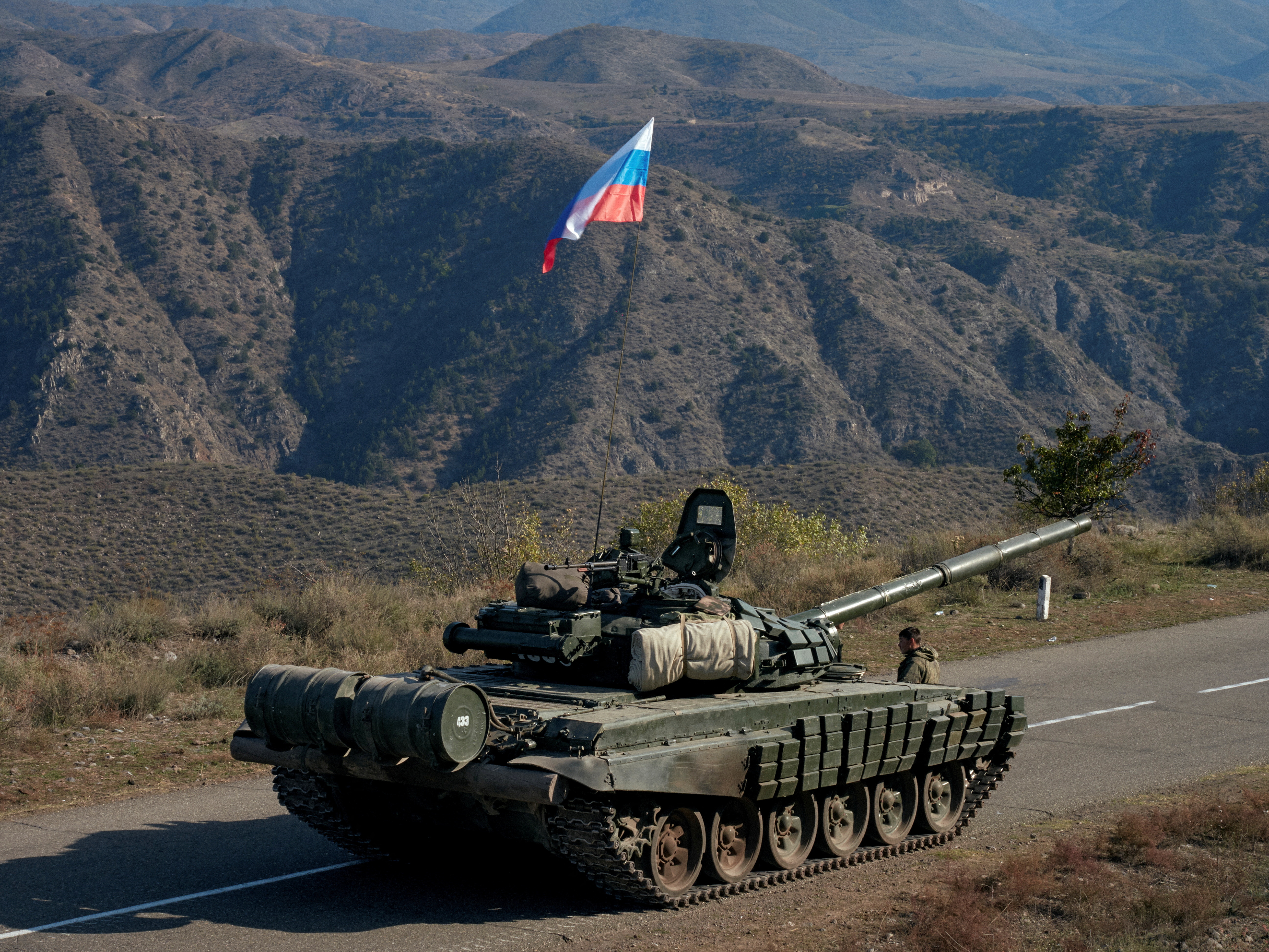 A service member of the Russian peacekeeping troops stands next to a tank in Nagorno-Karabakh