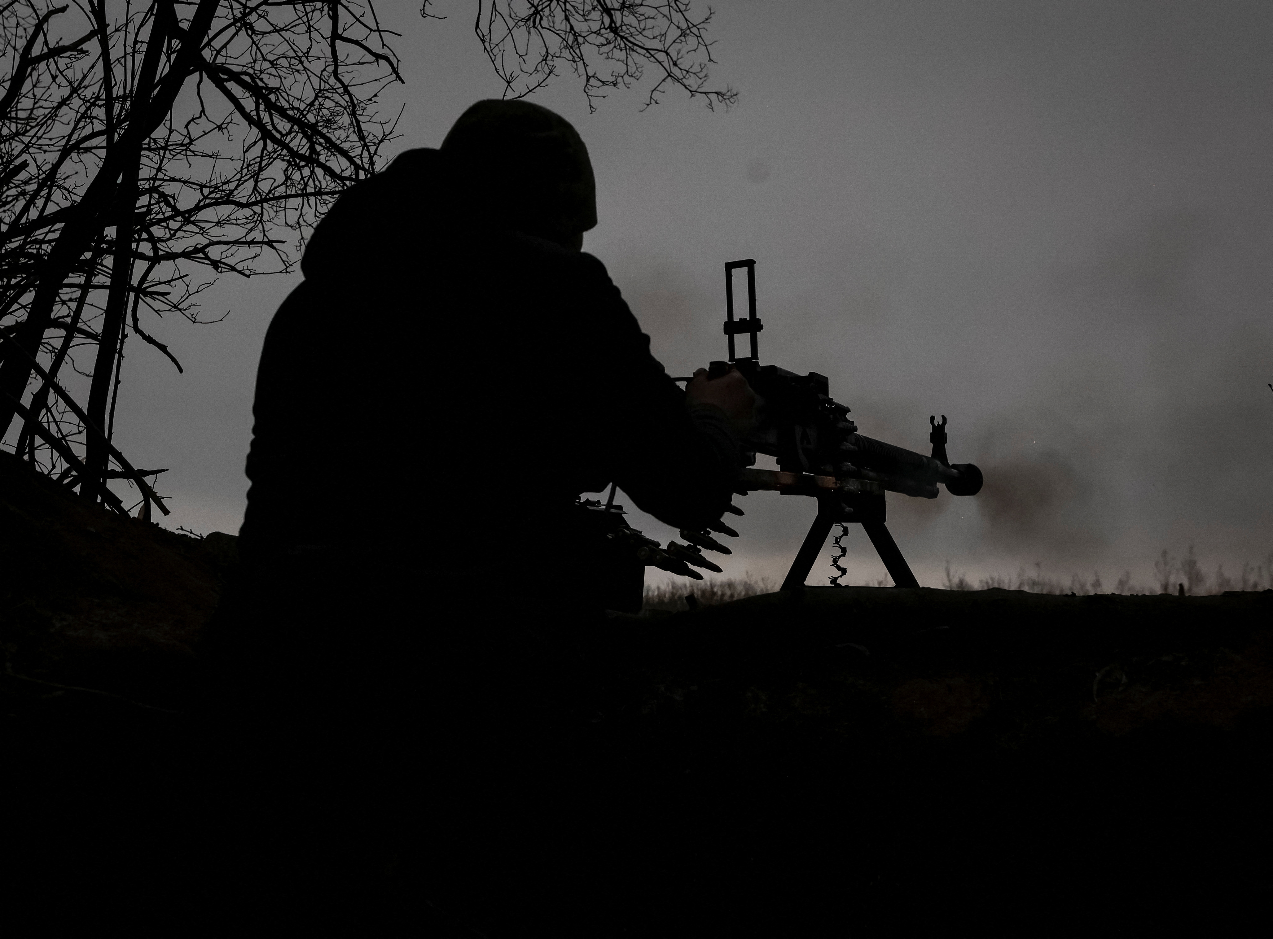 A Ukrainian service member fires a machine gun at a position on the front line near the town of Soledar