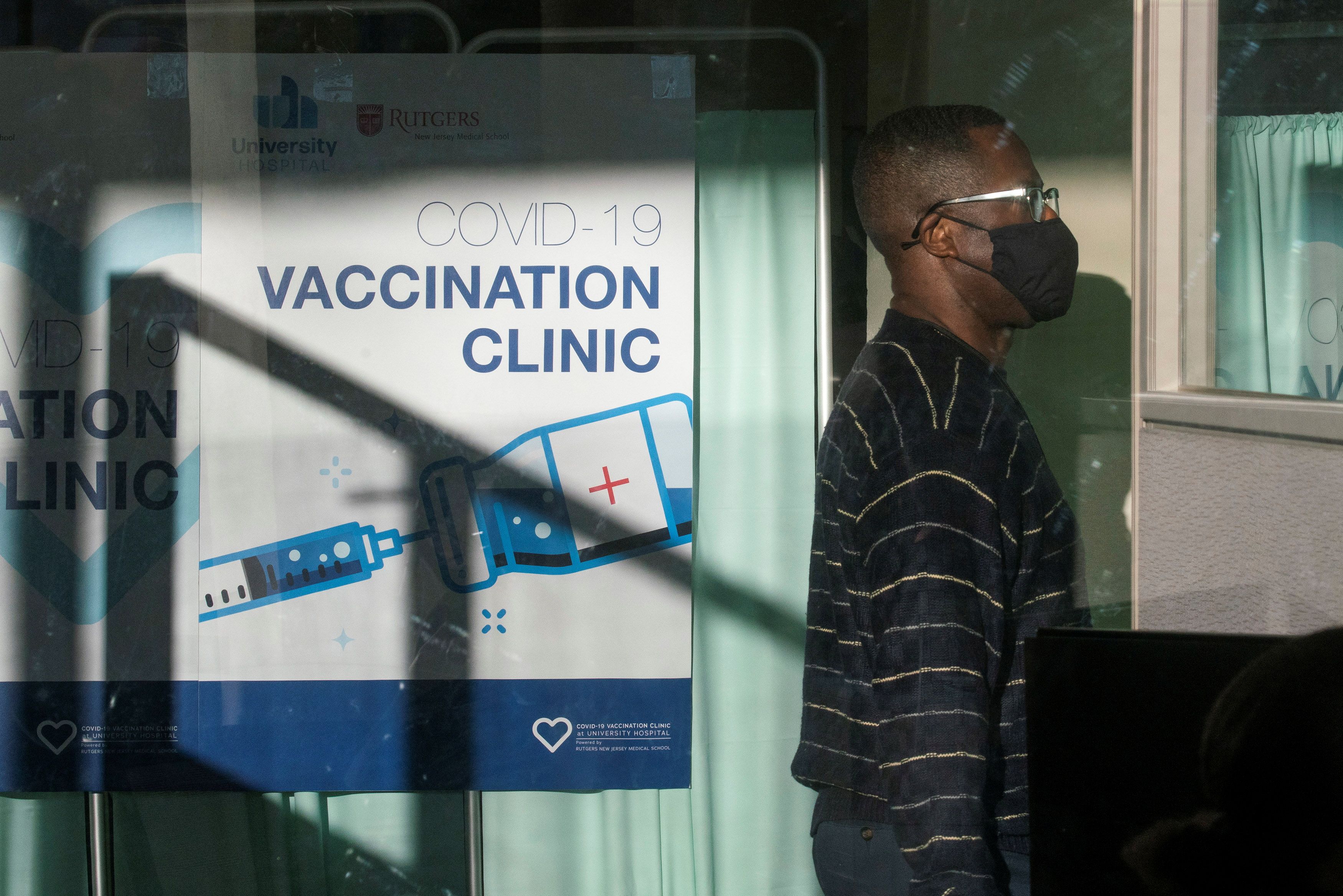 A man walks by the area where people get vaccine at University Hospital's COVID-19 vaccine clinic at Rutgers New Jersey Medical School in Newark, New Jersey
