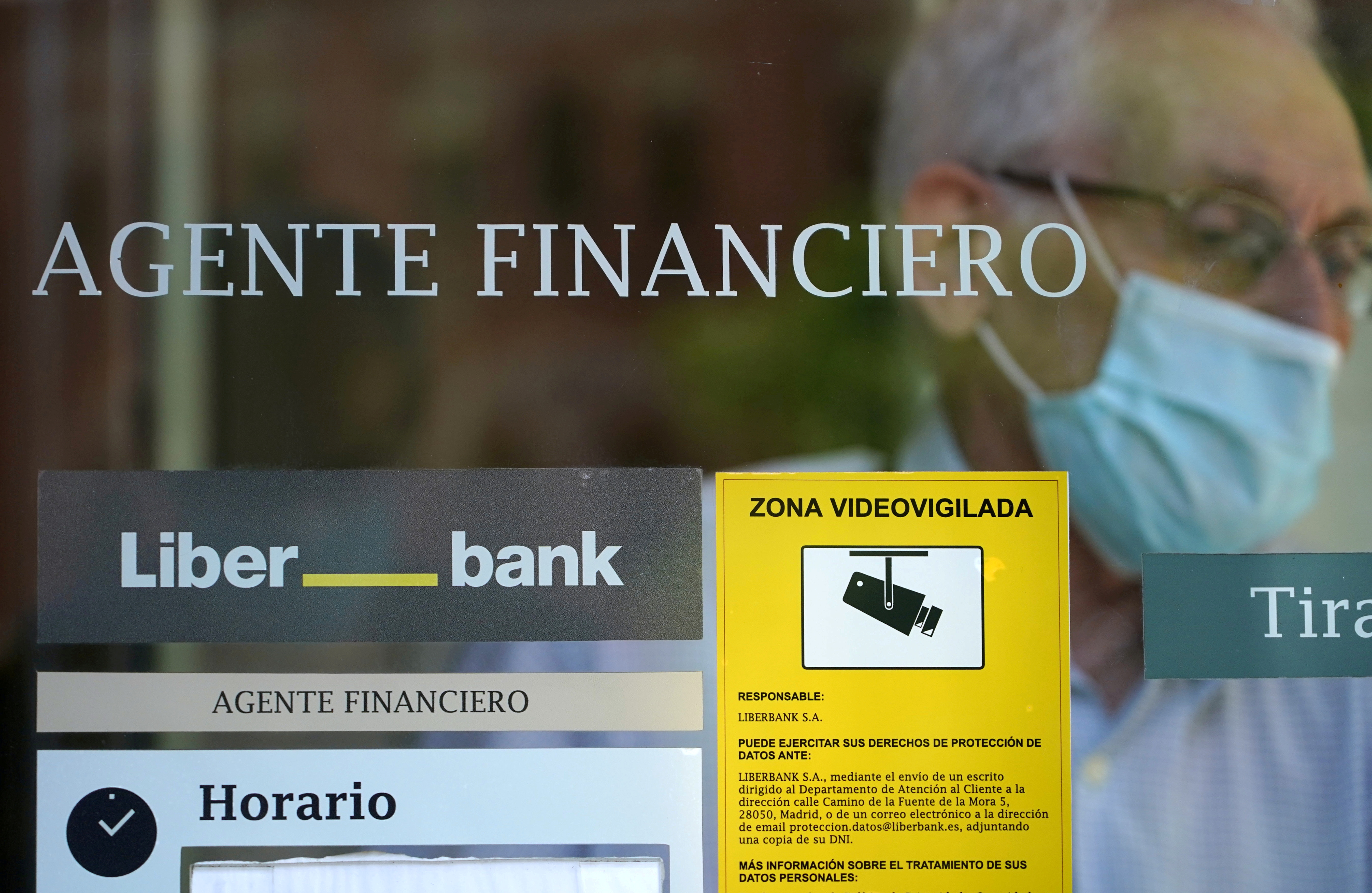 A man leaves the Liberbank financial agency branch in Madrid