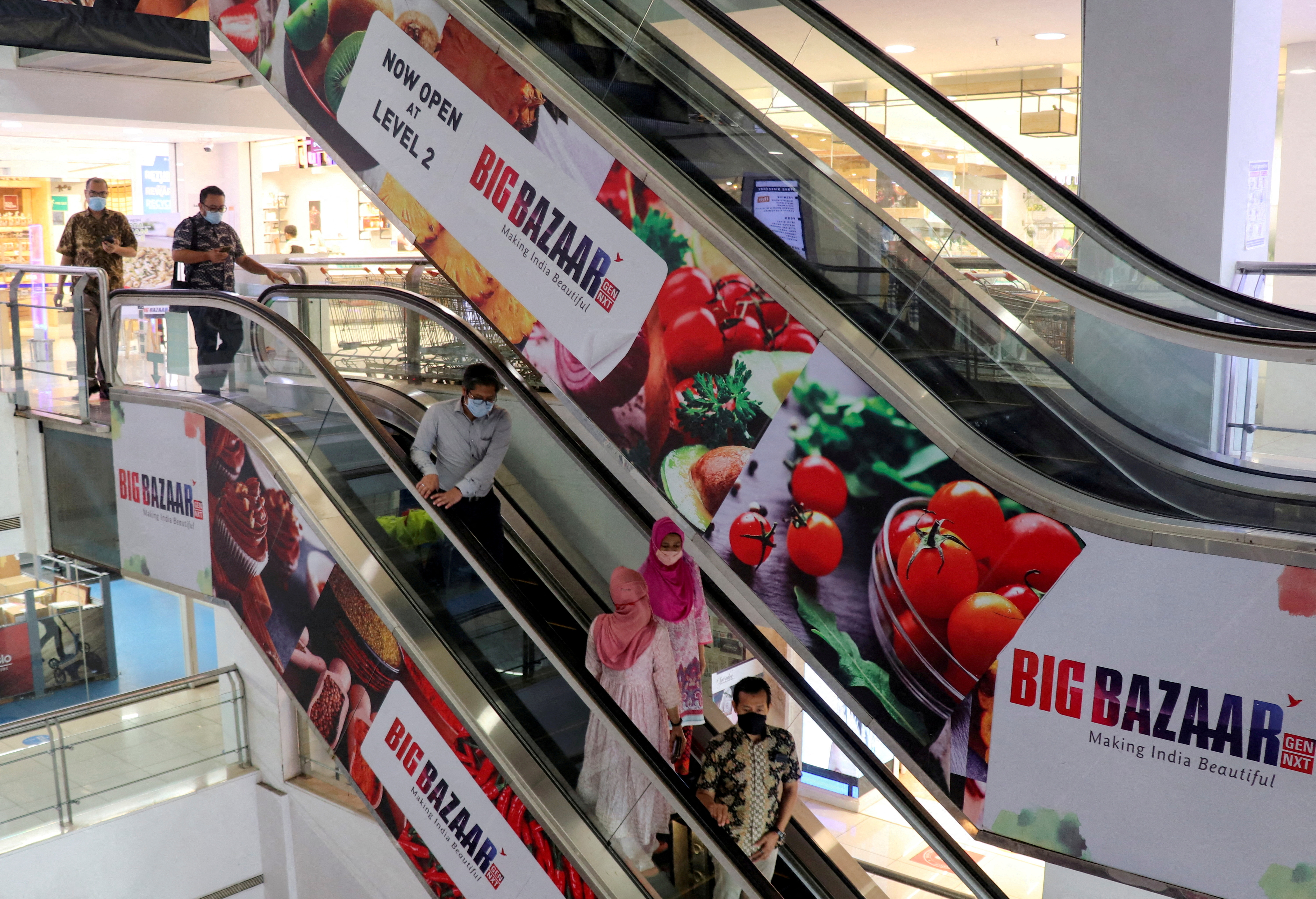 People use an escalator as they exit a Future Group Big Bazaar retail store in Mumbai