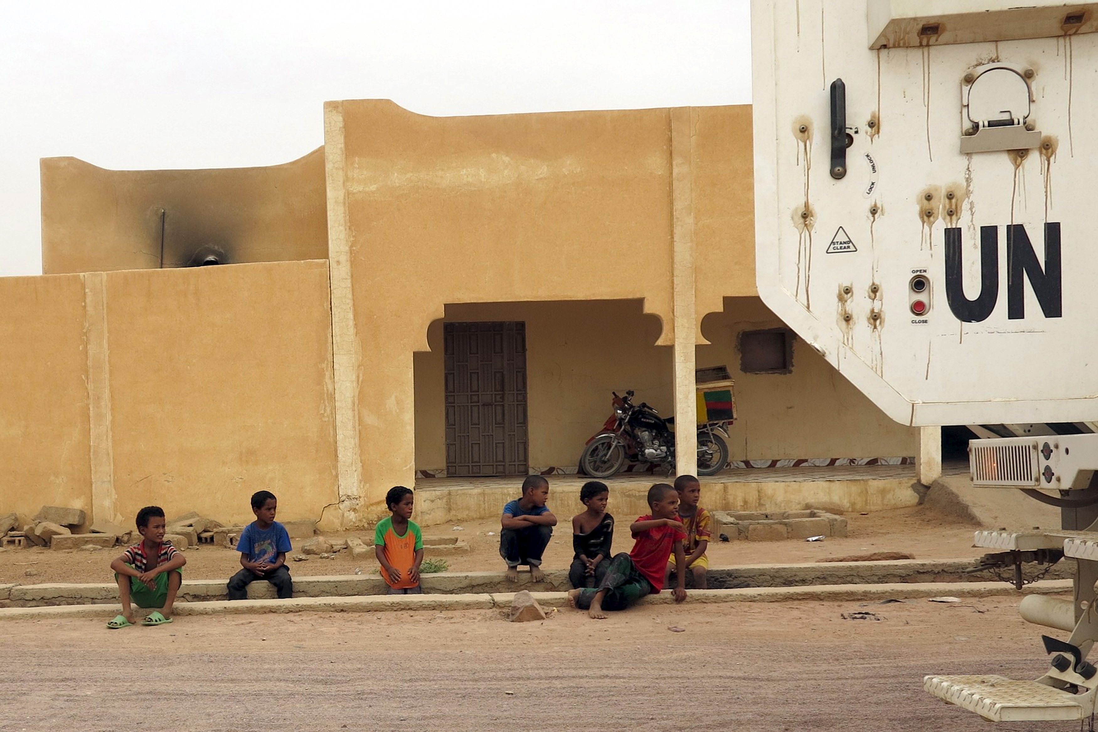 Children watch as a Minusma peacekeeping armored vehicle drive past in Kidal