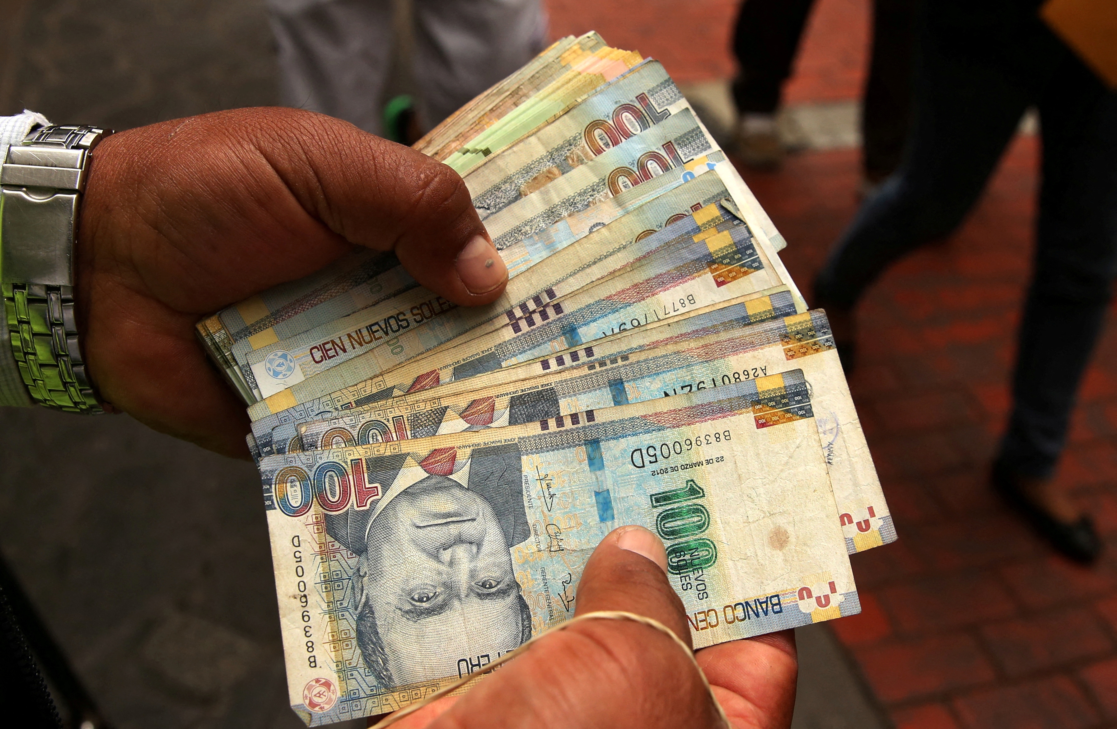 A money changer holds Peruvian Sol bills at a street in downtown Lima