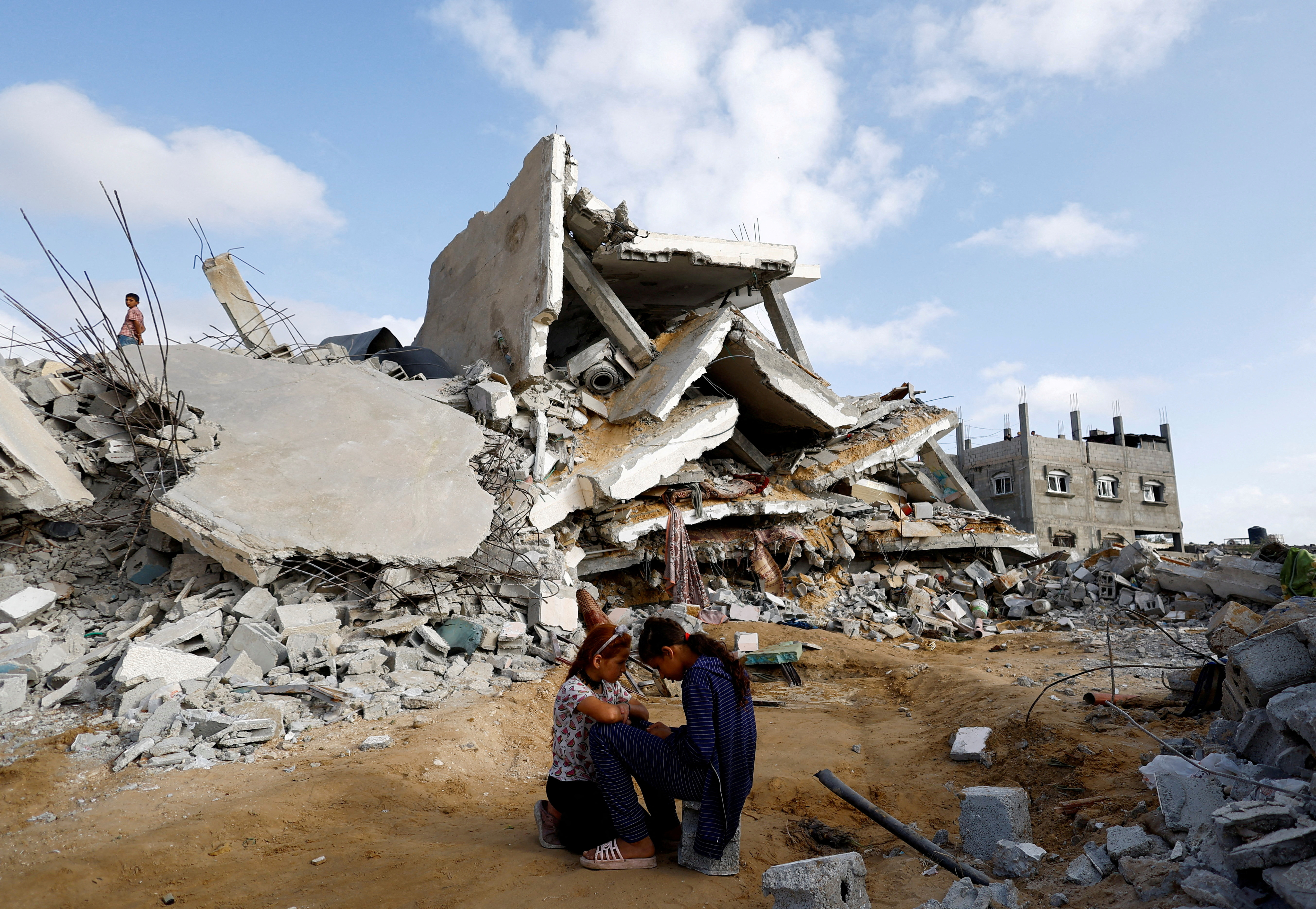 Palestinian children sit next to the site of an Israeli strike on a house, in Rafah