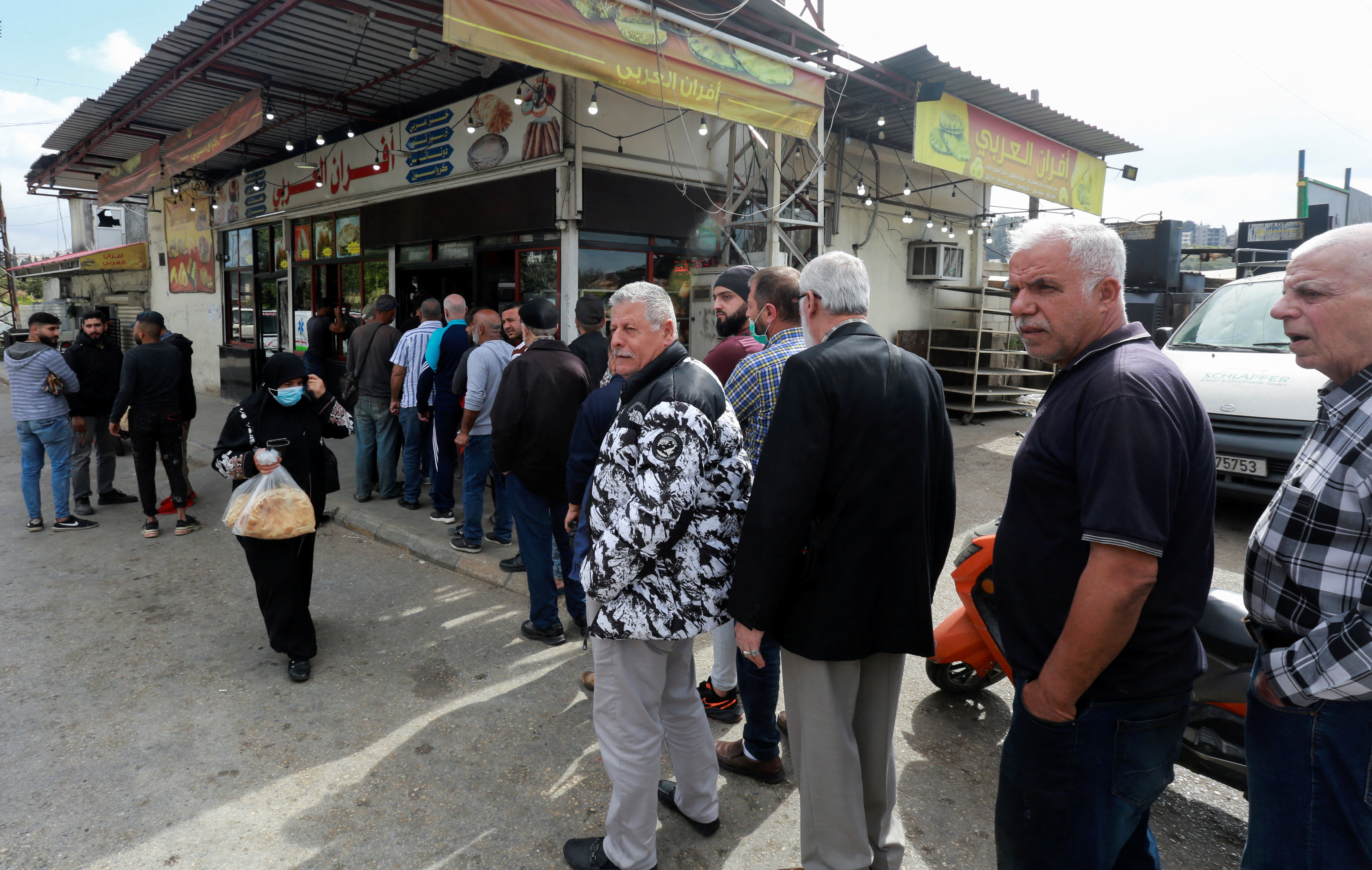 People queue to buy bread outside a bakery in Sidon