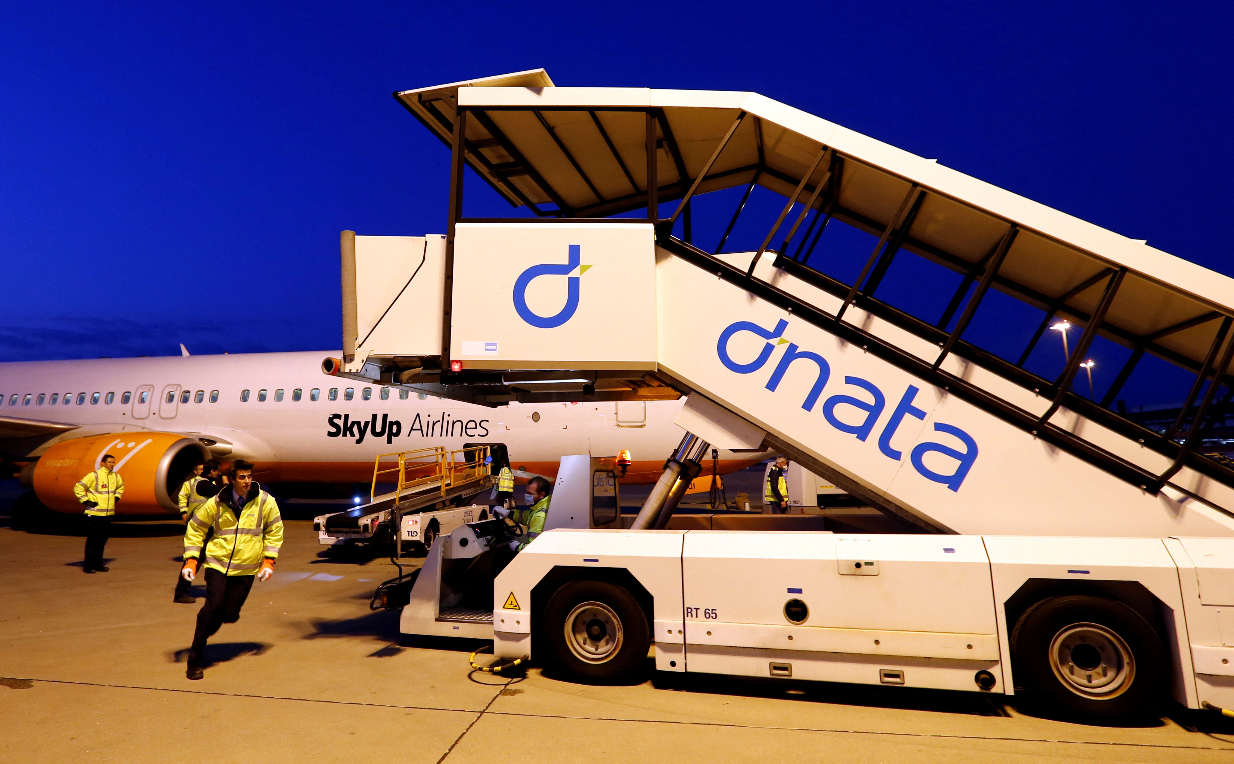 Dnata staff load cargo into a plane on the tarmac of Cointrin Airport in Geneva