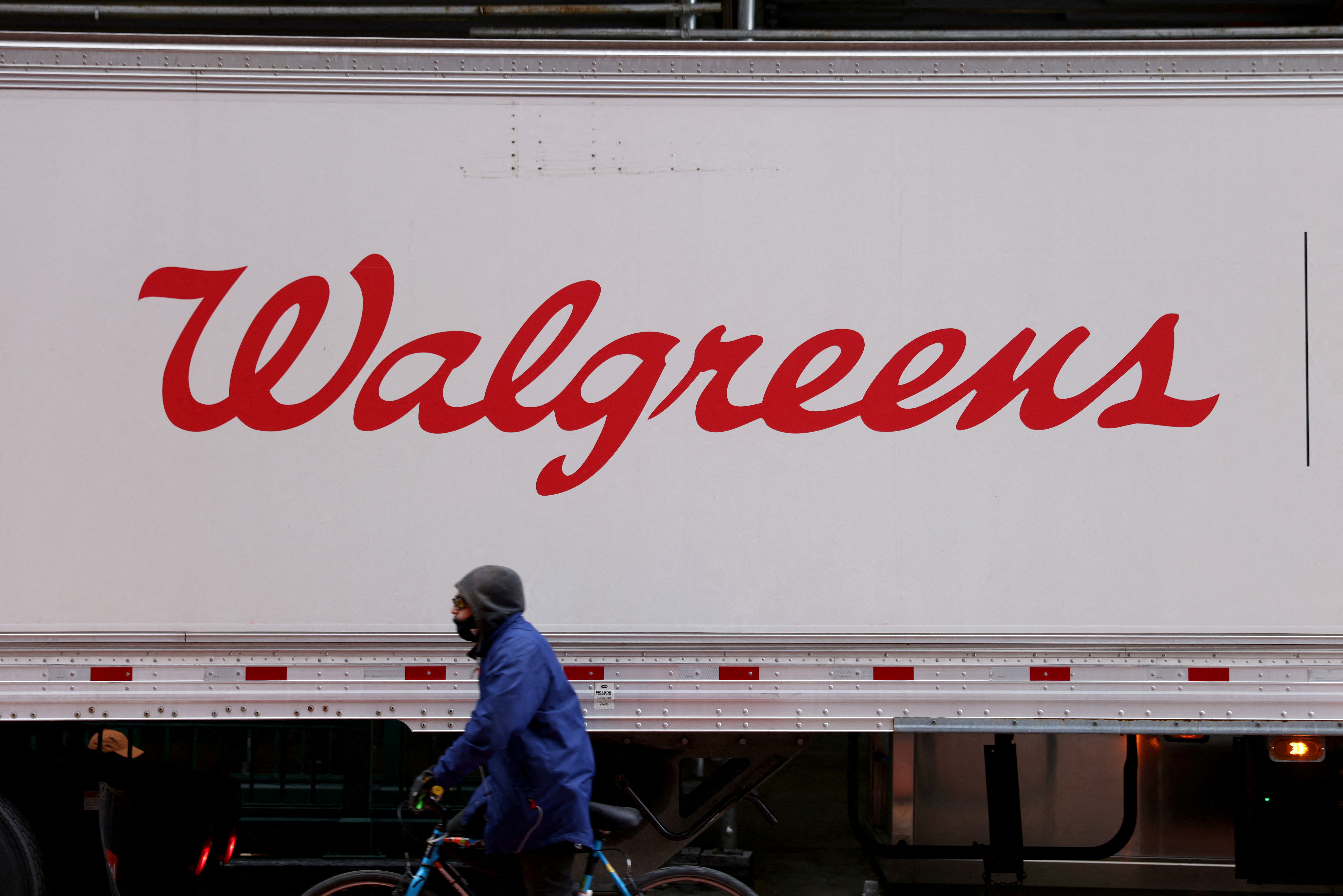 A person rides past a Walgreens truck, owned by the Walgreens Boots Alliance, Inc., in Manhattan, New York City, U.S., November 26, 2021. REUTERS/Andrew Kelly