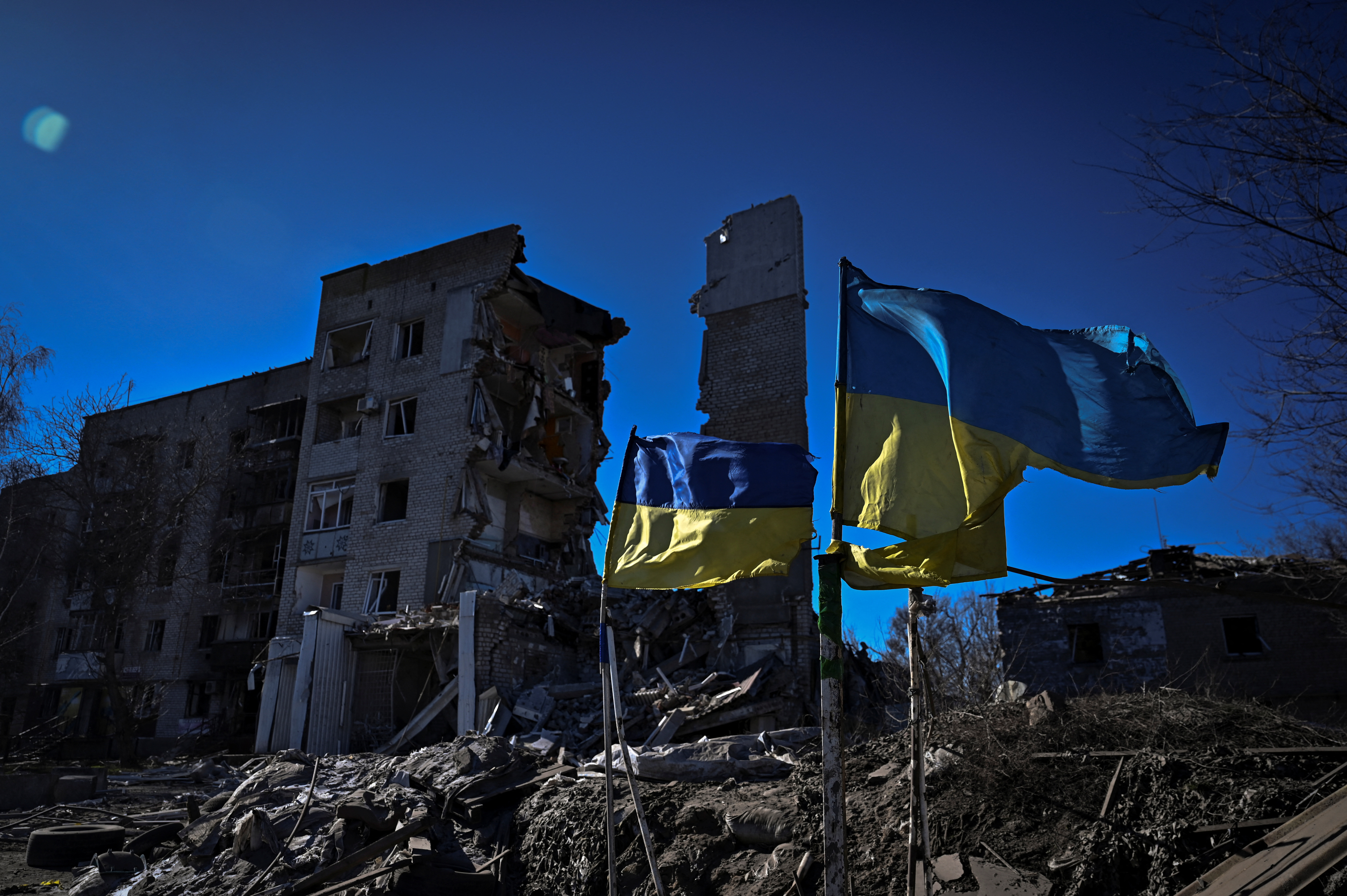 Ukrainian national flutter rise in front of a heavily damaged apartment building in the frontline town of Orikhiv