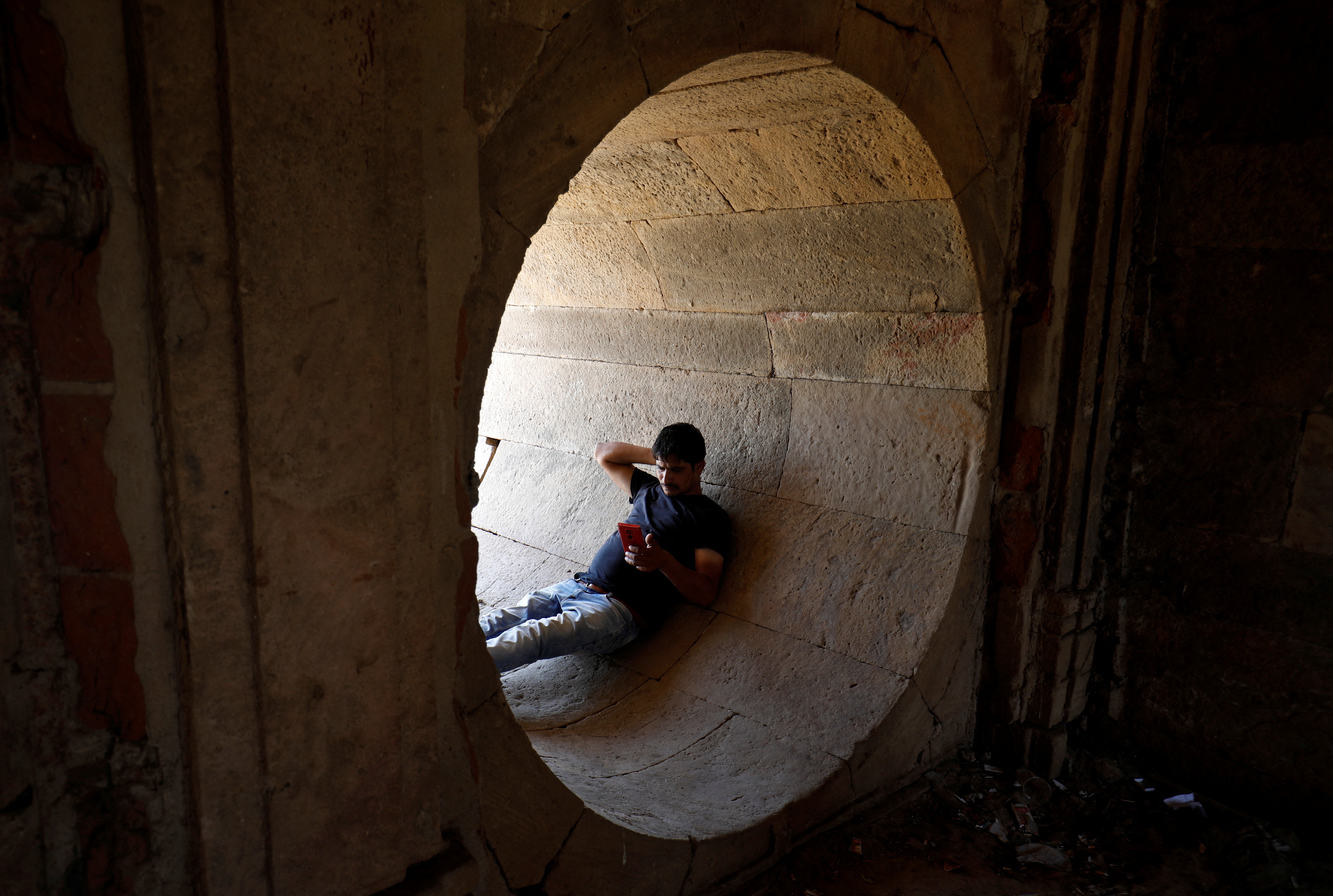 A man rests in a dry water tunnel of Sarkhej Roza lake during hot weather in Ahmedabad