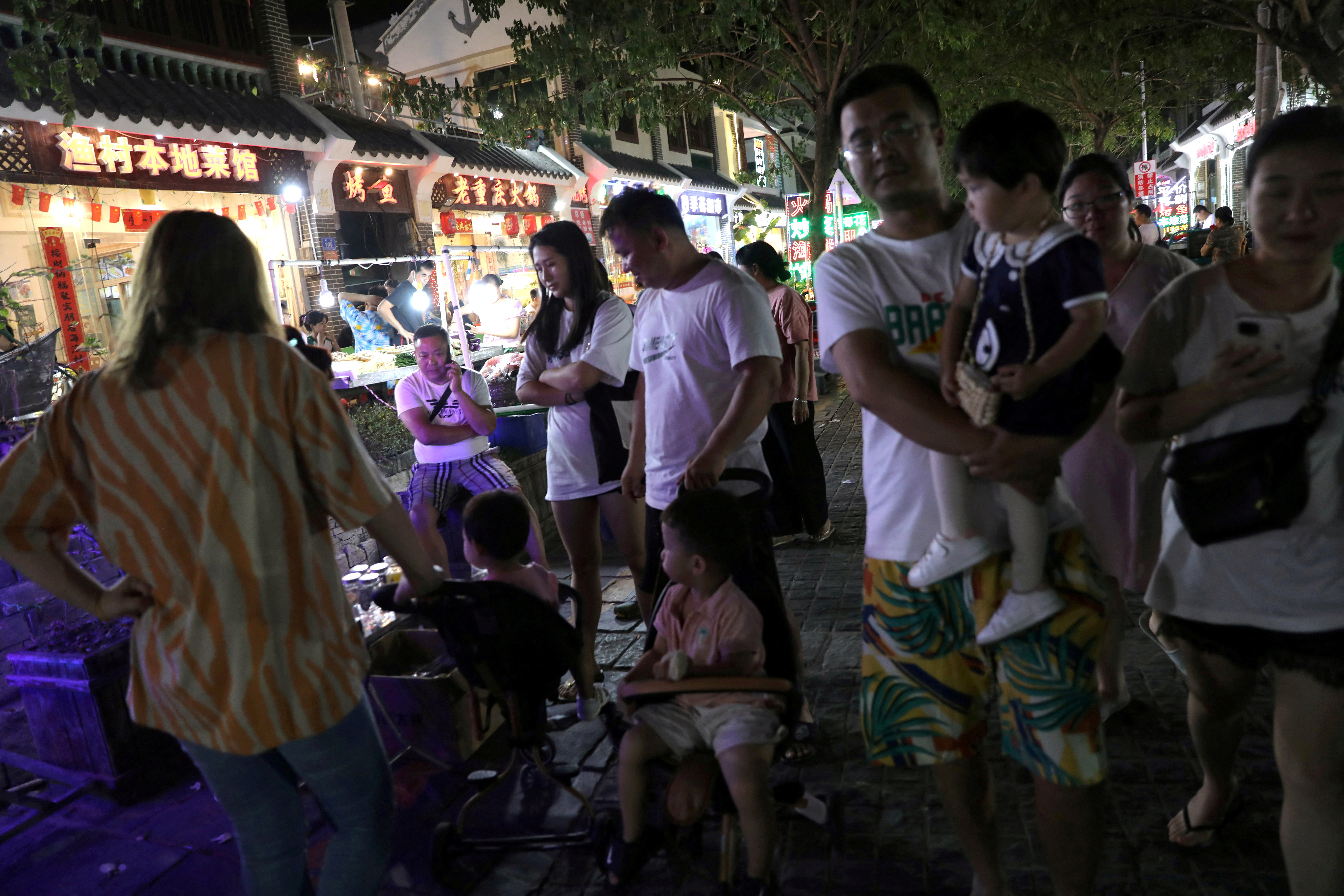 People are seen next to restaurants at Houhai village in Sanya