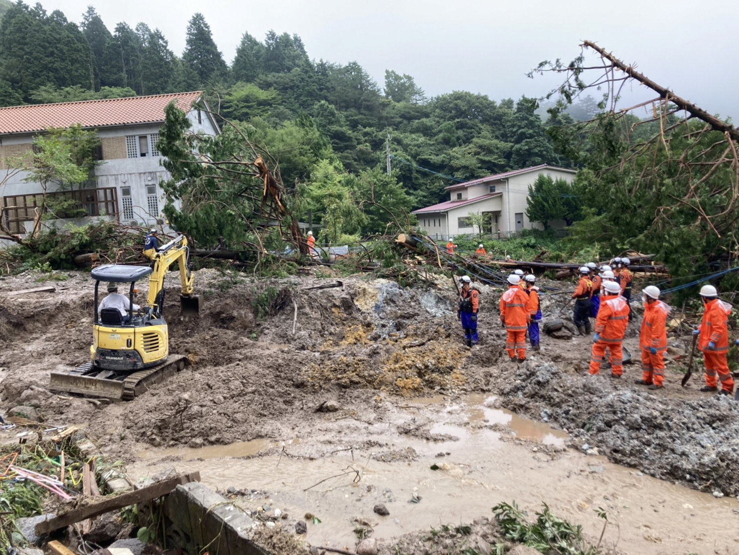 Rescue workers search for missing people at a landslide site caused by heavy rainfall in Unzen