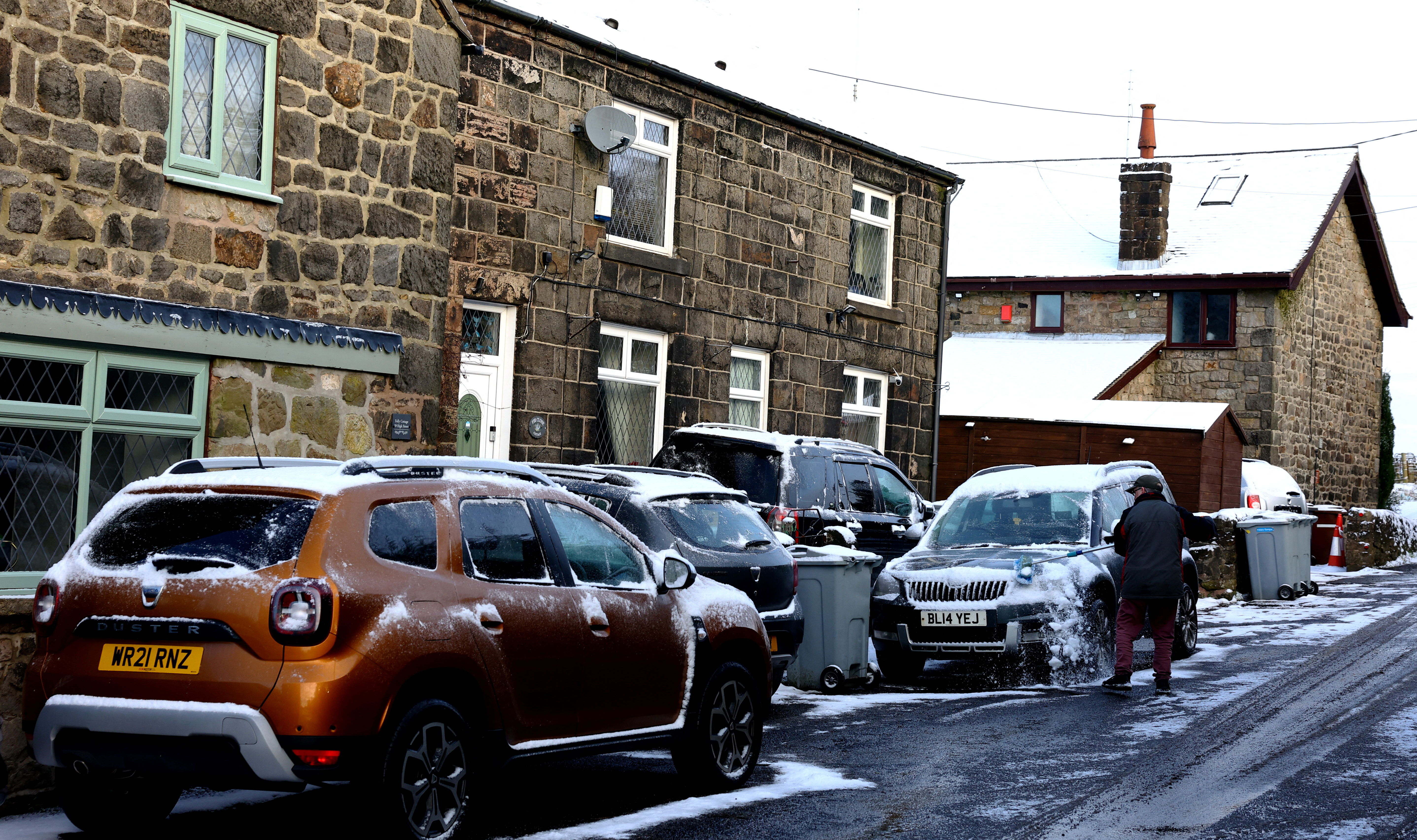 A man clears his car of snow in Mow Cop