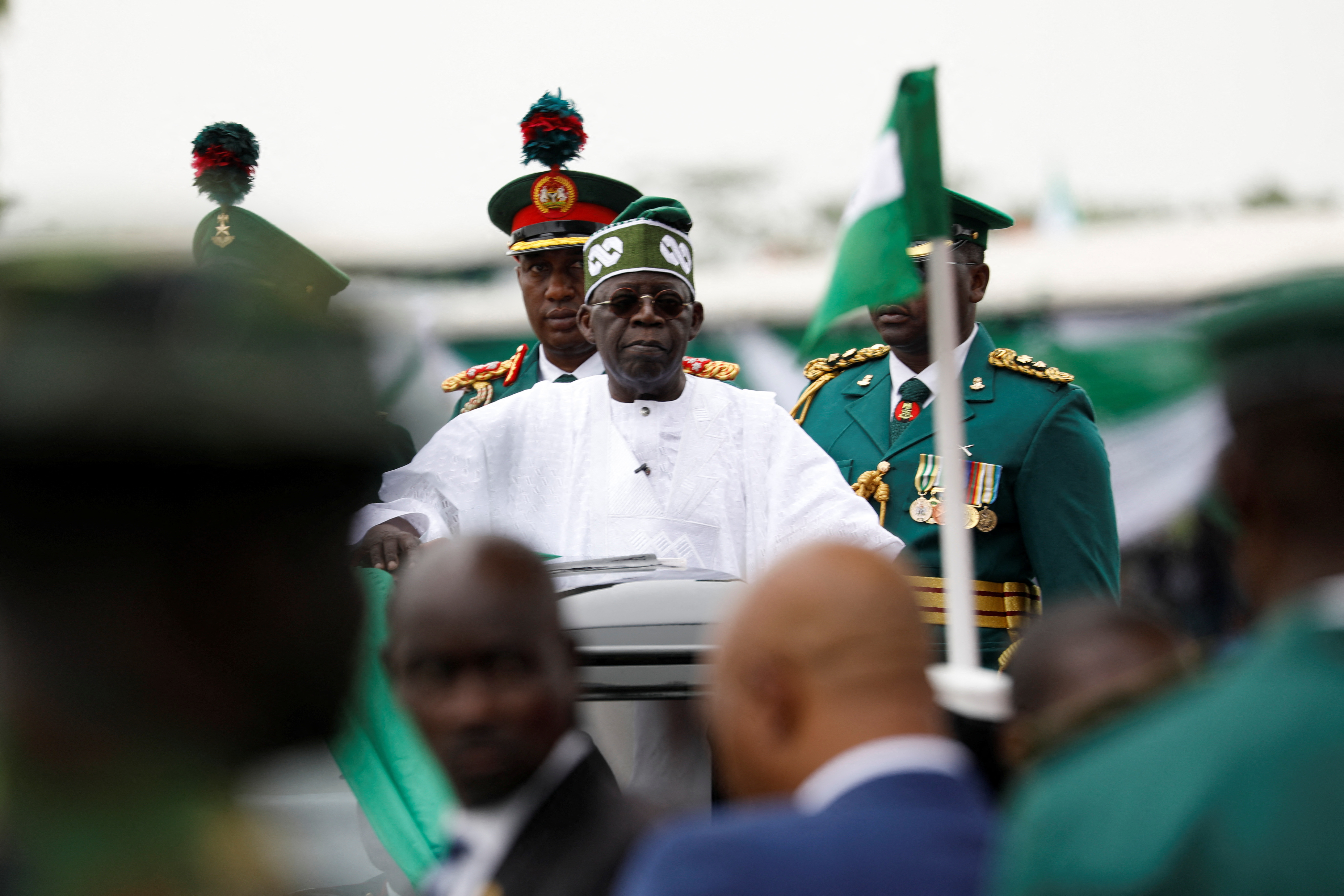 Nigeria's President Bola Tinubu looks on as he takes the traditional ride on top of a ceremonial vehicle after his swearing-in ceremony in Abuja
