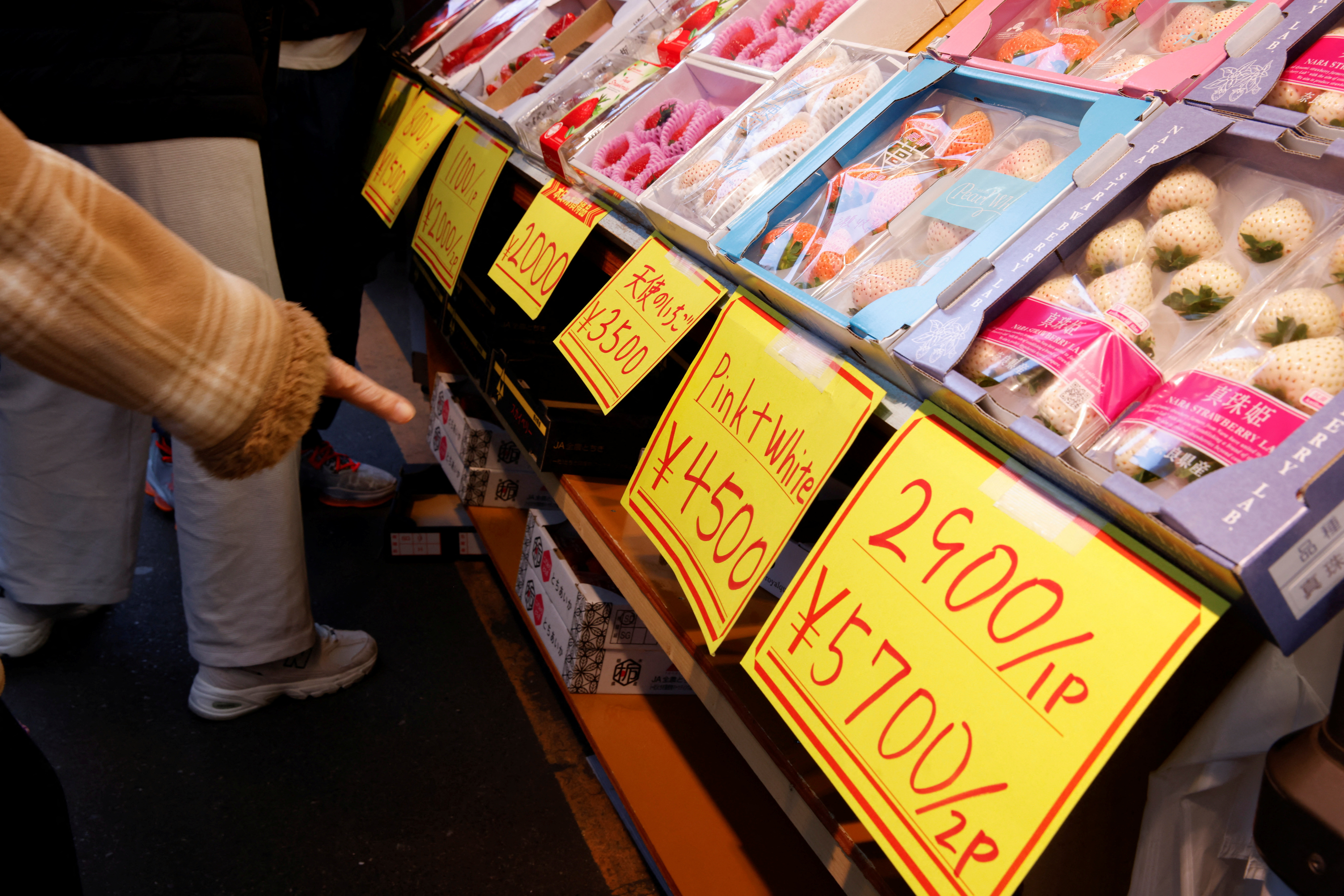 A woman points out the high prices of fruits at a Tokyo market.