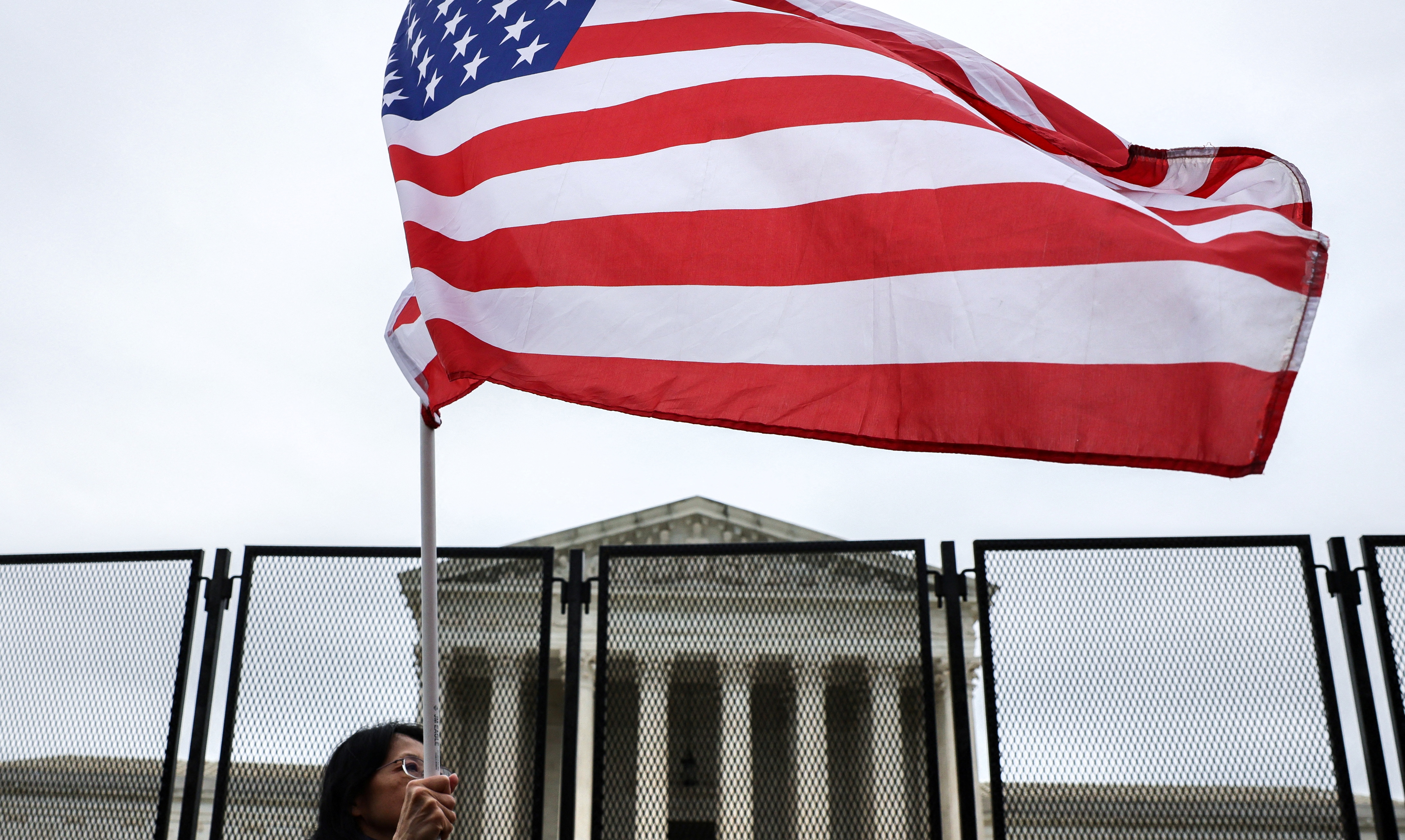 An anti-abortion protester waves a flag in front of the U.S. Supreme Court, in Washington