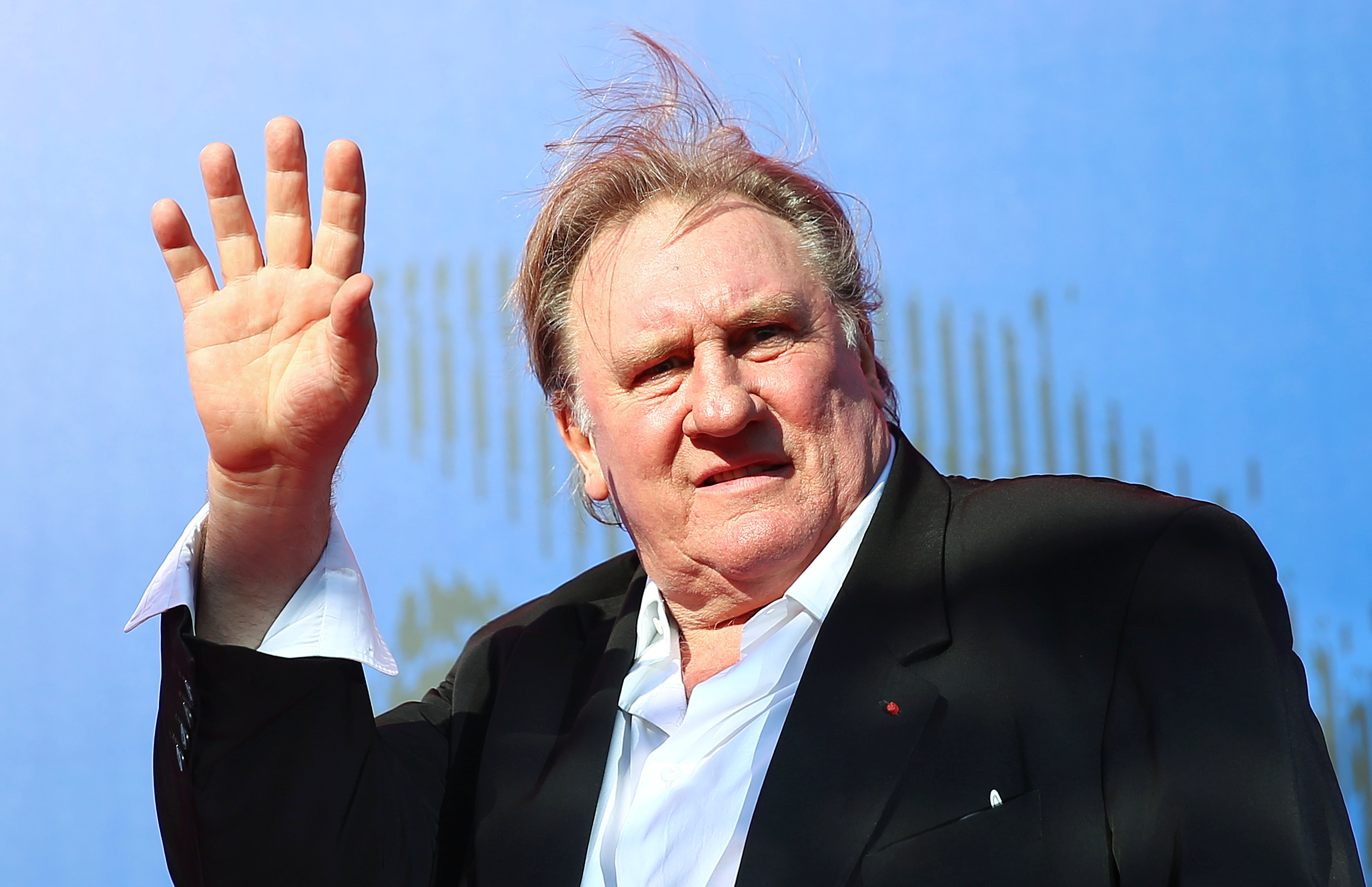 Gerard Depardieu waves as he arrives during a red carpet event for the movie 