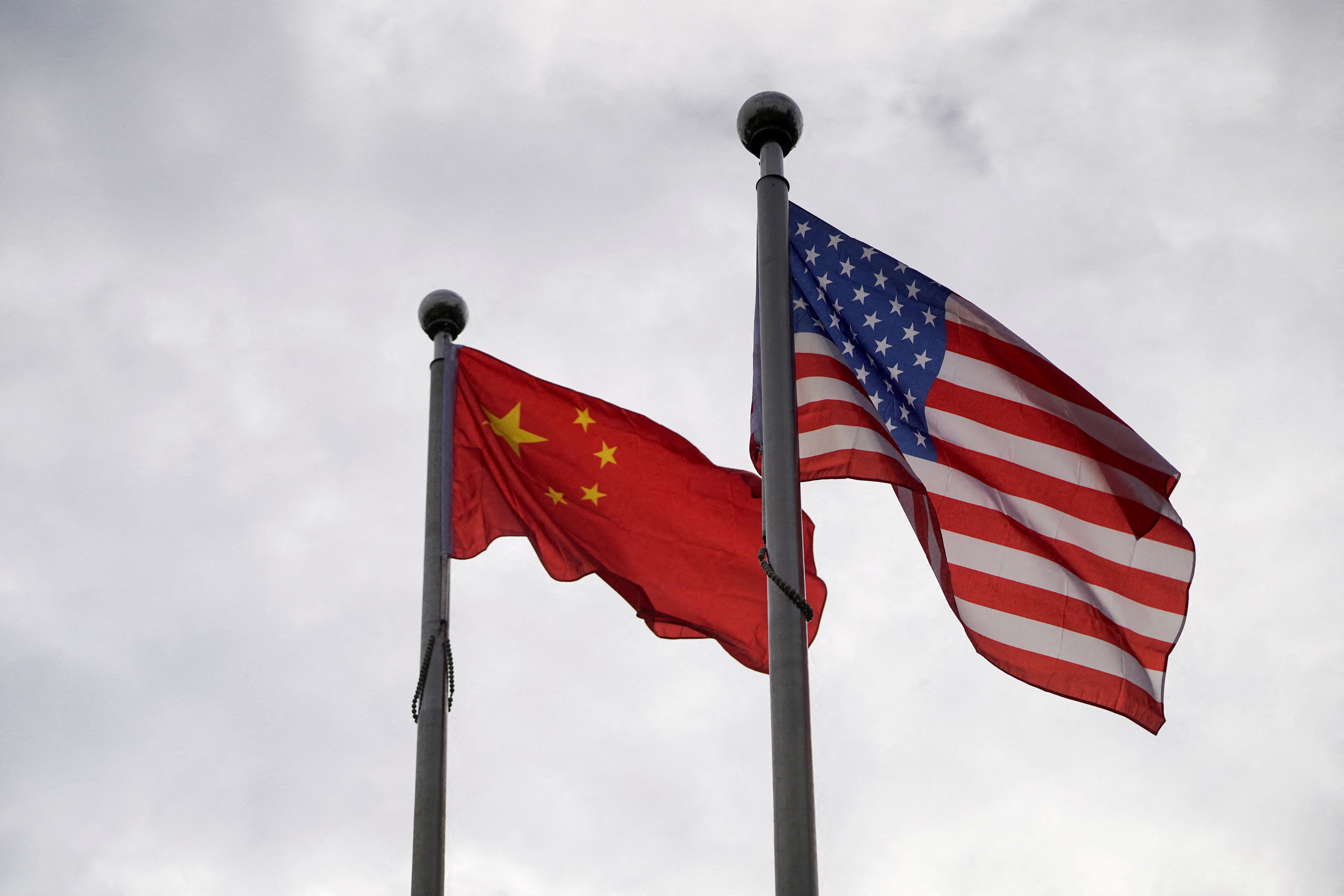 Chinese and U.S. flags flutter outside a company building in Shanghai, China November 16, 2021. REUTERS/Aly Song