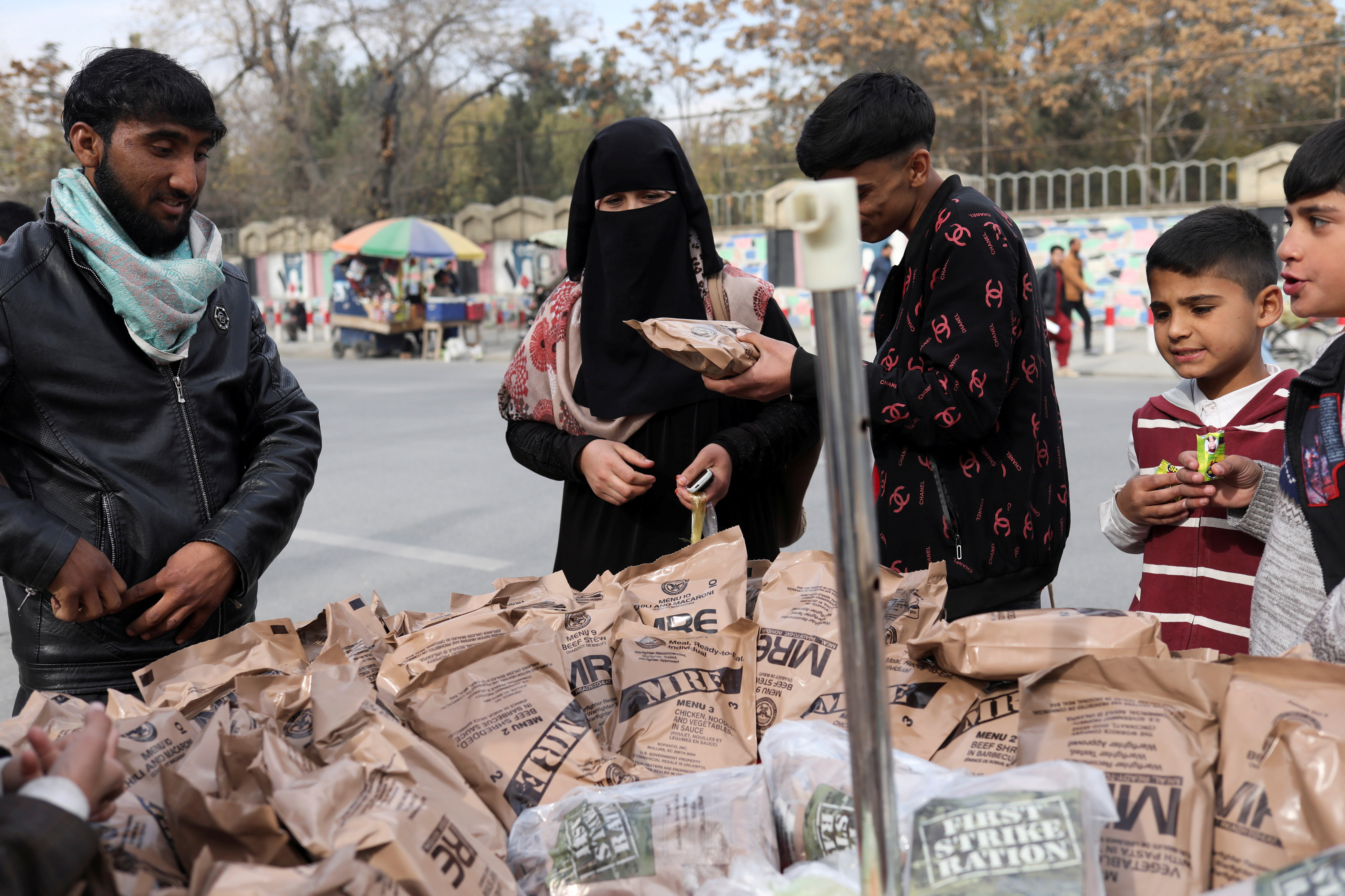 Afghan woman buys food left behind by the US military from a peddler in Kabul