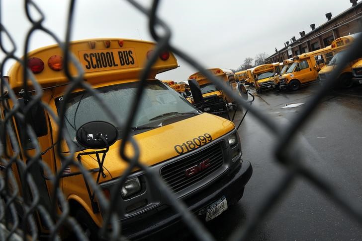 School buses are seen parked behind a locked bus depot fence in the Queens borough of New York