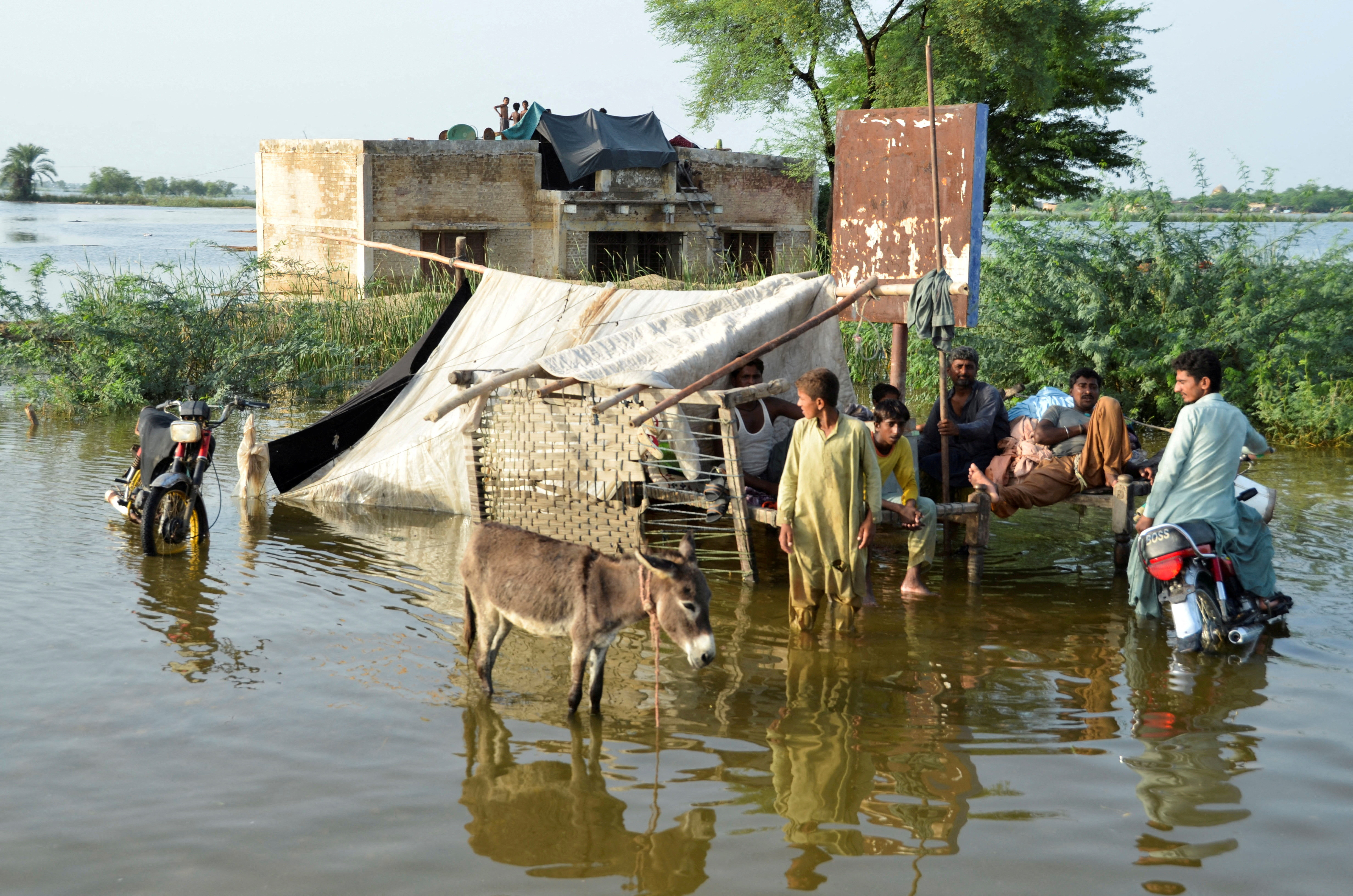 People are seen outside their flooded house, following rains and floods during the monsoon season in Sohbatpur