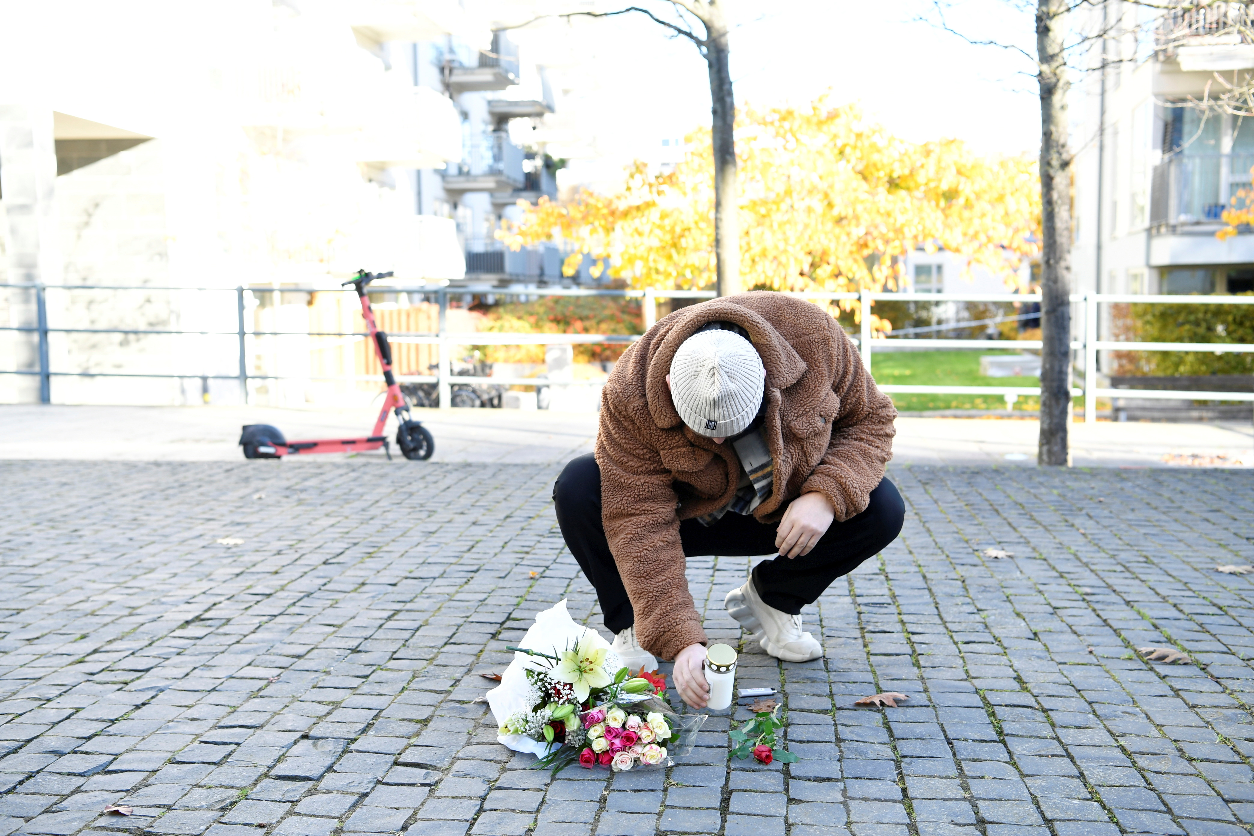A man places flowers and a candle at the site, where Swedish rapper Einar was reportedly shot dead in the street on Thursday night, in the Hammarby Sjostad distict in Stockholm