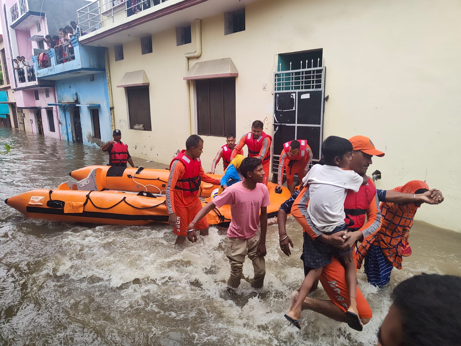 Members of National Disaster Response Force evacuate people to safer places from a flooded area in Udham Singh Nagar
