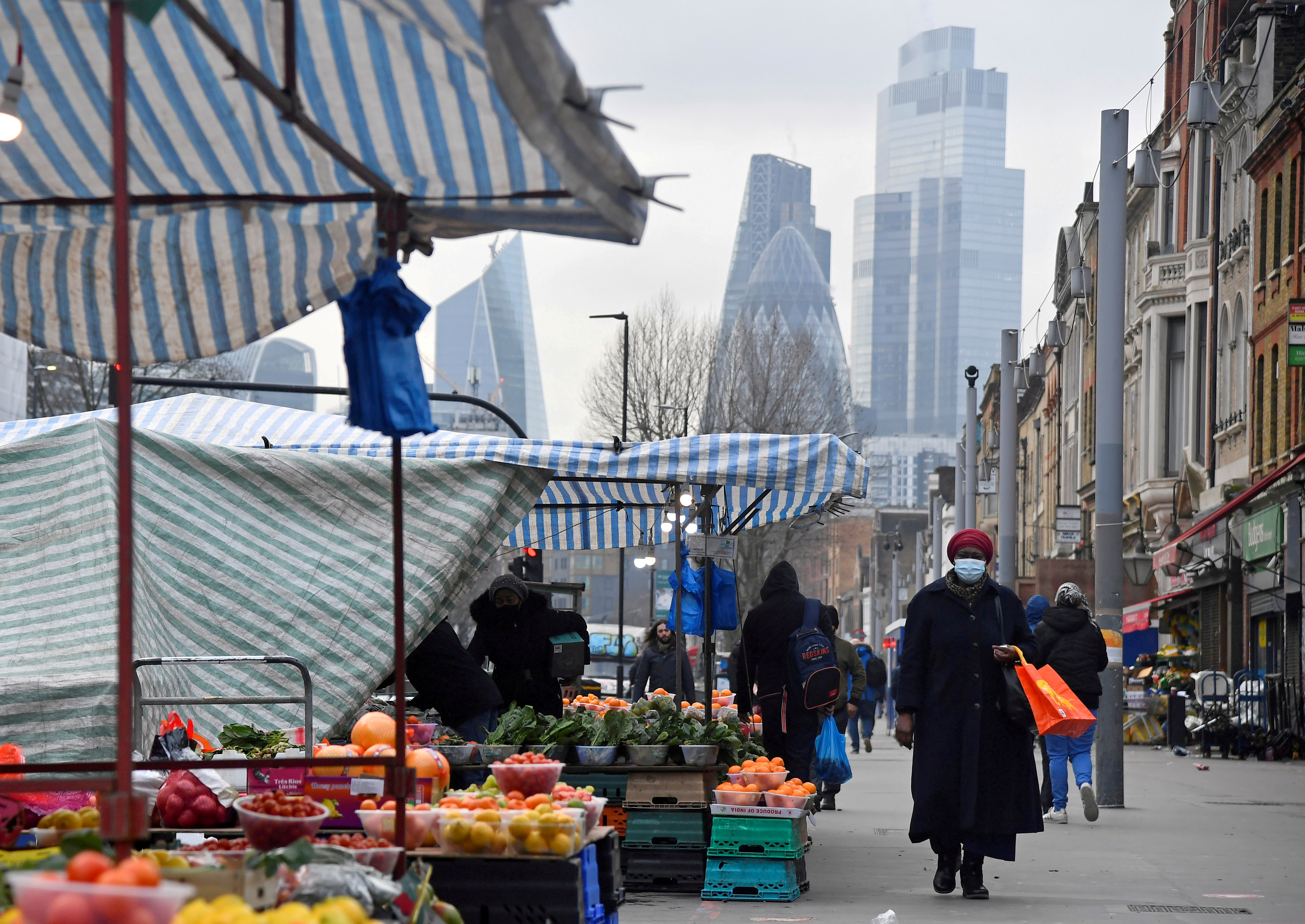 People shop at market stalls, with skyscrapers of the CIty of London financial district seen behind, amid the coronavirus disease (COVID-19) pandemic, in London, Britain, January 15, 2021. REUTERS/Toby Melville