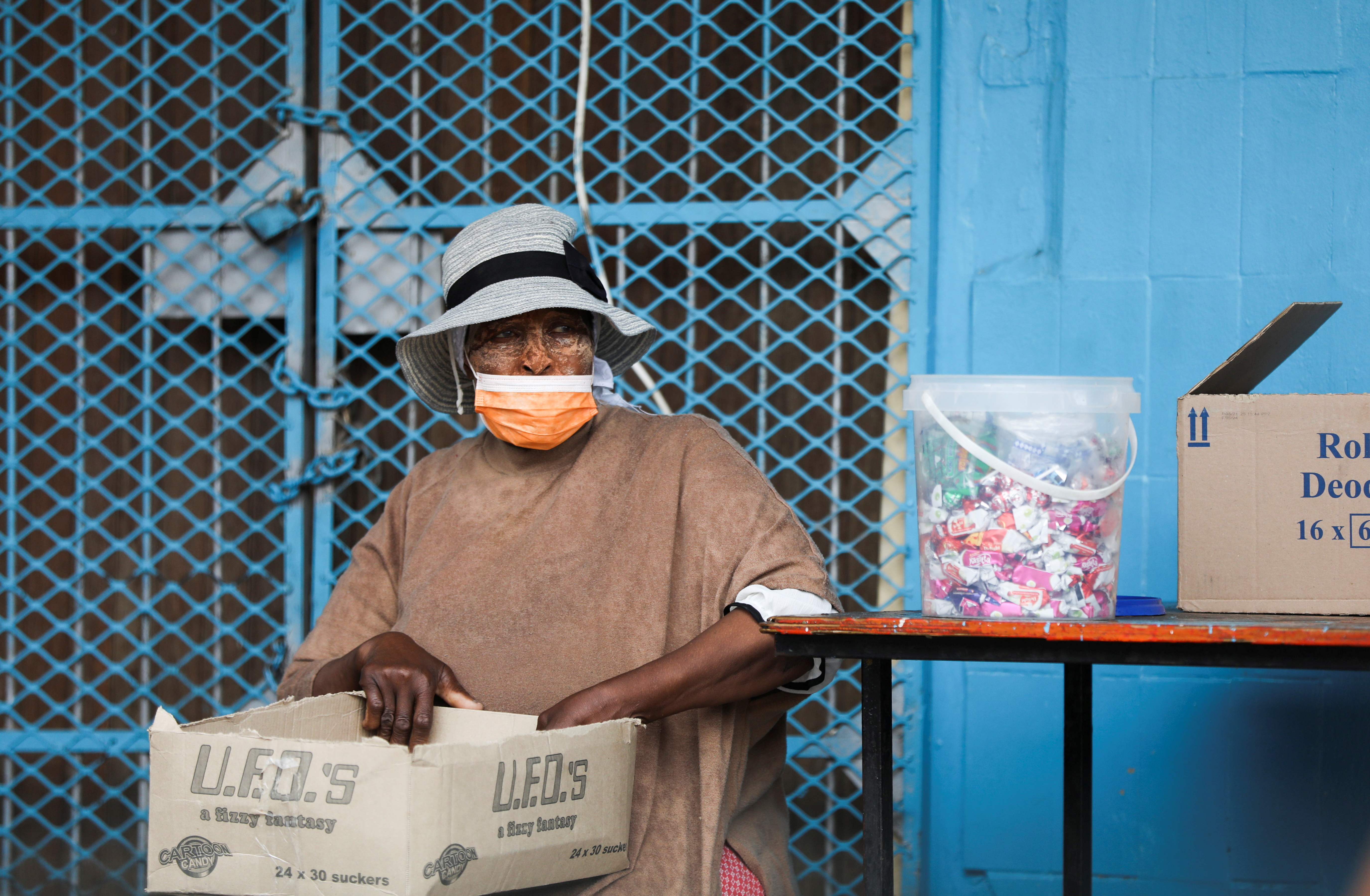 A woman wearing a protective face mask against the coronavirus disease (COVID-19) sits next to her stall, as the new Omicron coronavirus variant spreads, at Tsomo