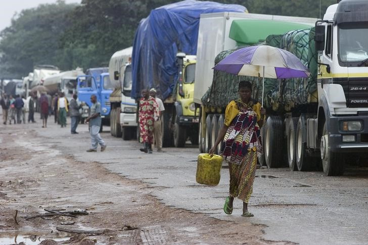 A woman walks past trucks waiting to cross into the Democratic Republic of Congo from Zambia at the Kasumbalesa border post