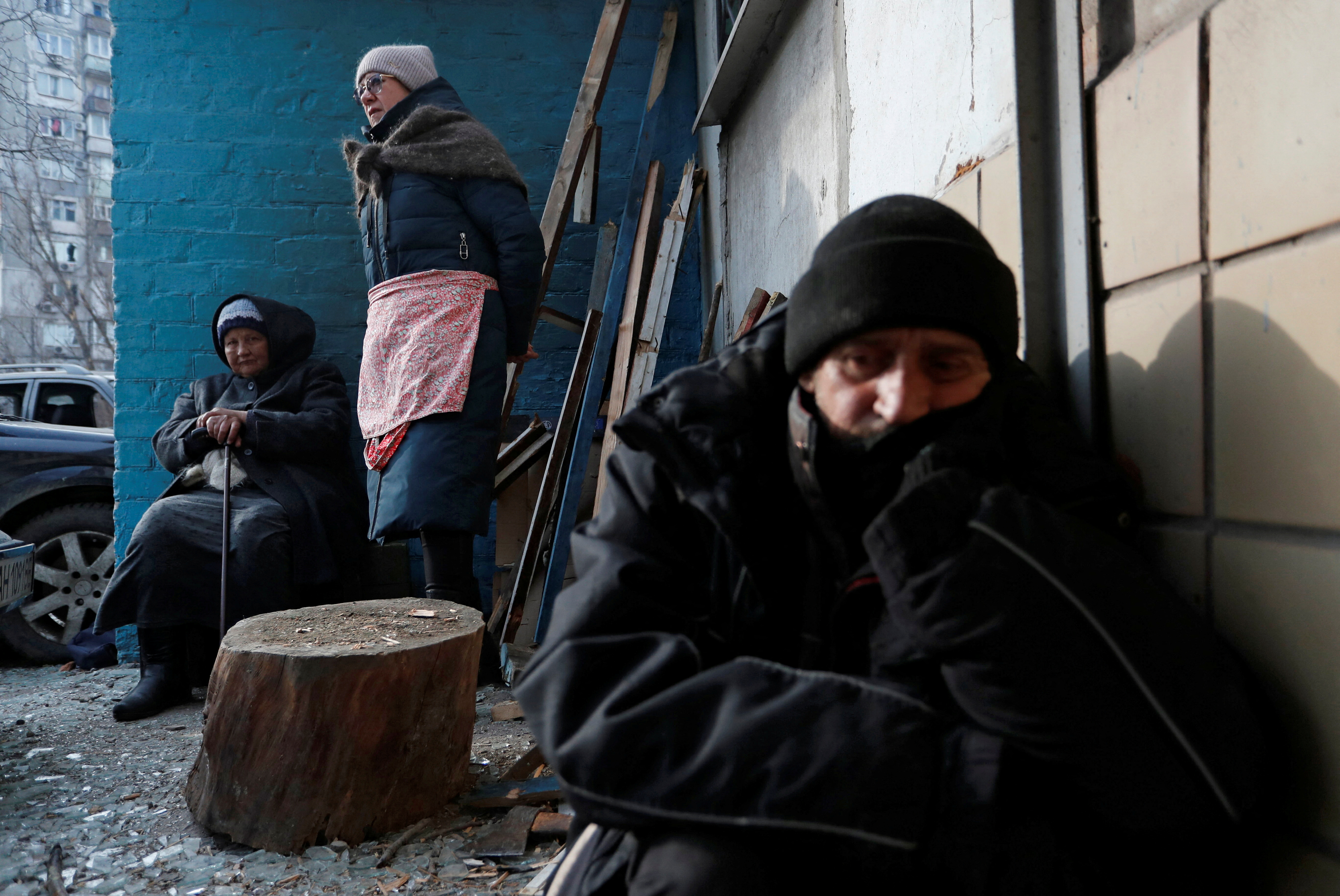 Local residents are seen outside a damaged apartment building in Mariupol