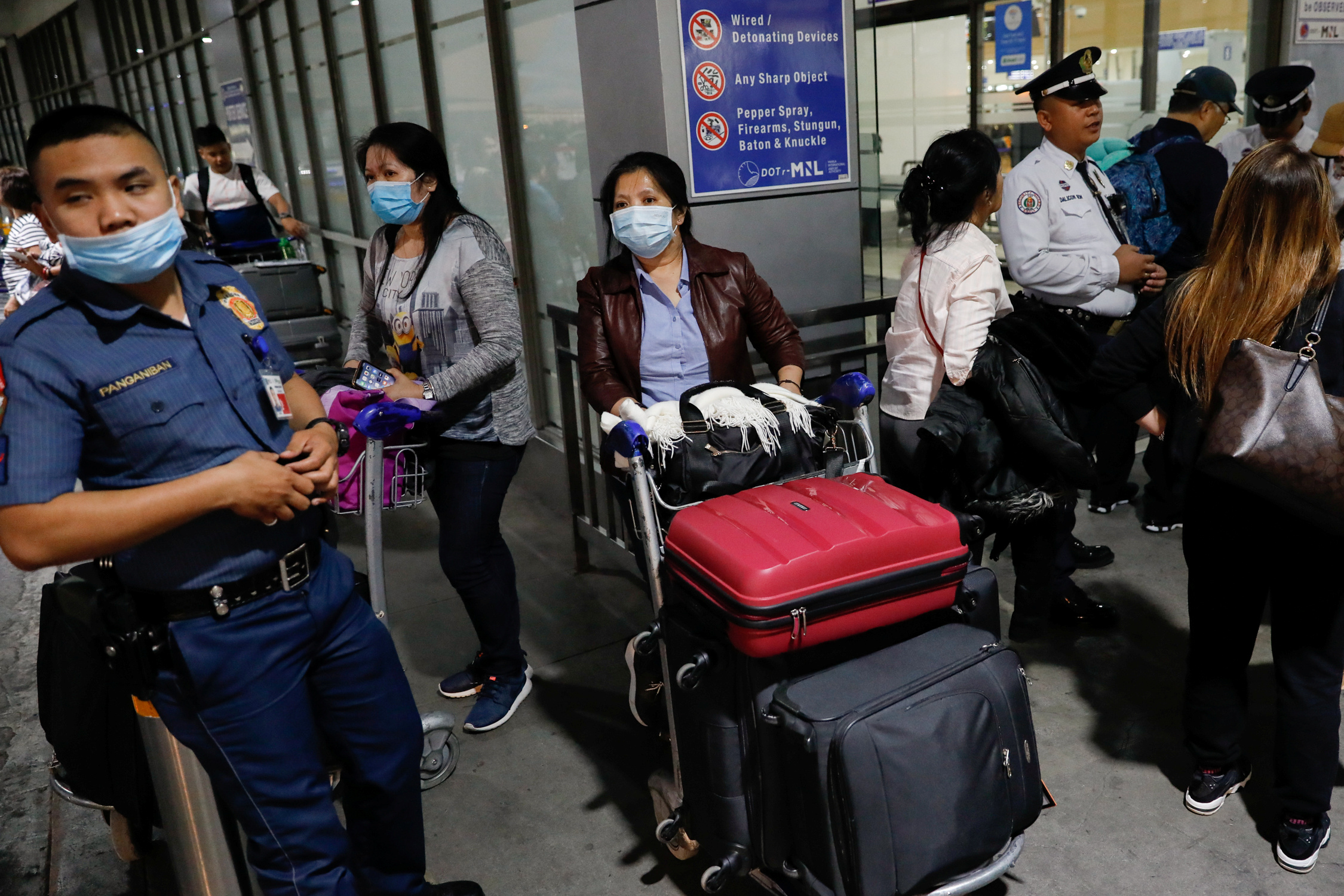 Overseas Filipino Workers (OFW) wearing protective masks standby outside the Ninoy Aquino International Airport in Pasay City