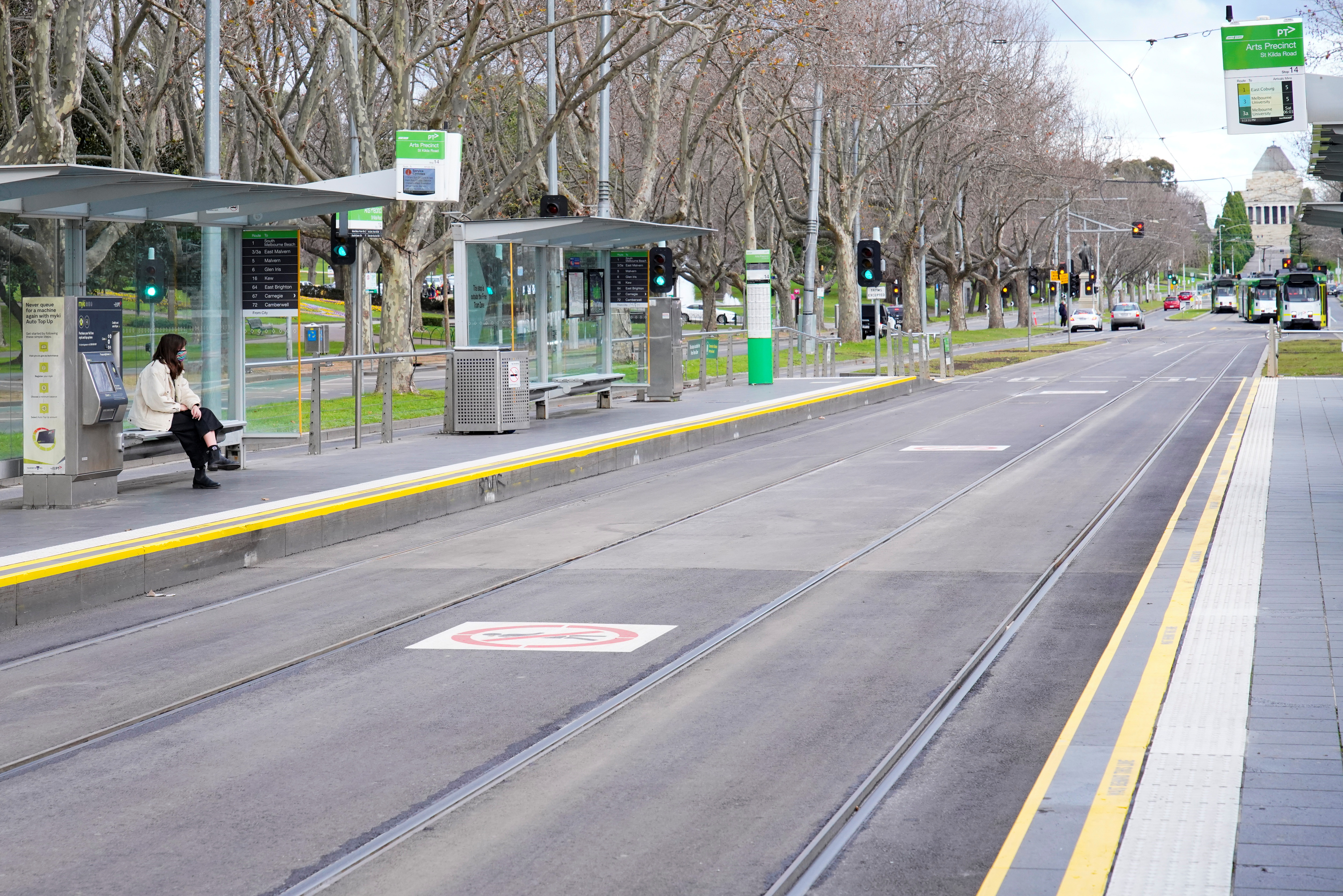 A lone passenger sits at a tram stop on a mostly-empty city centre street on the first day of a lockdown as the state of Victoria looks to curb the spread of a coronavirus disease (COVID-19) outbreak in Melbourne, Australia, July 16, 2021.  REUTERS/Sandra Sanders