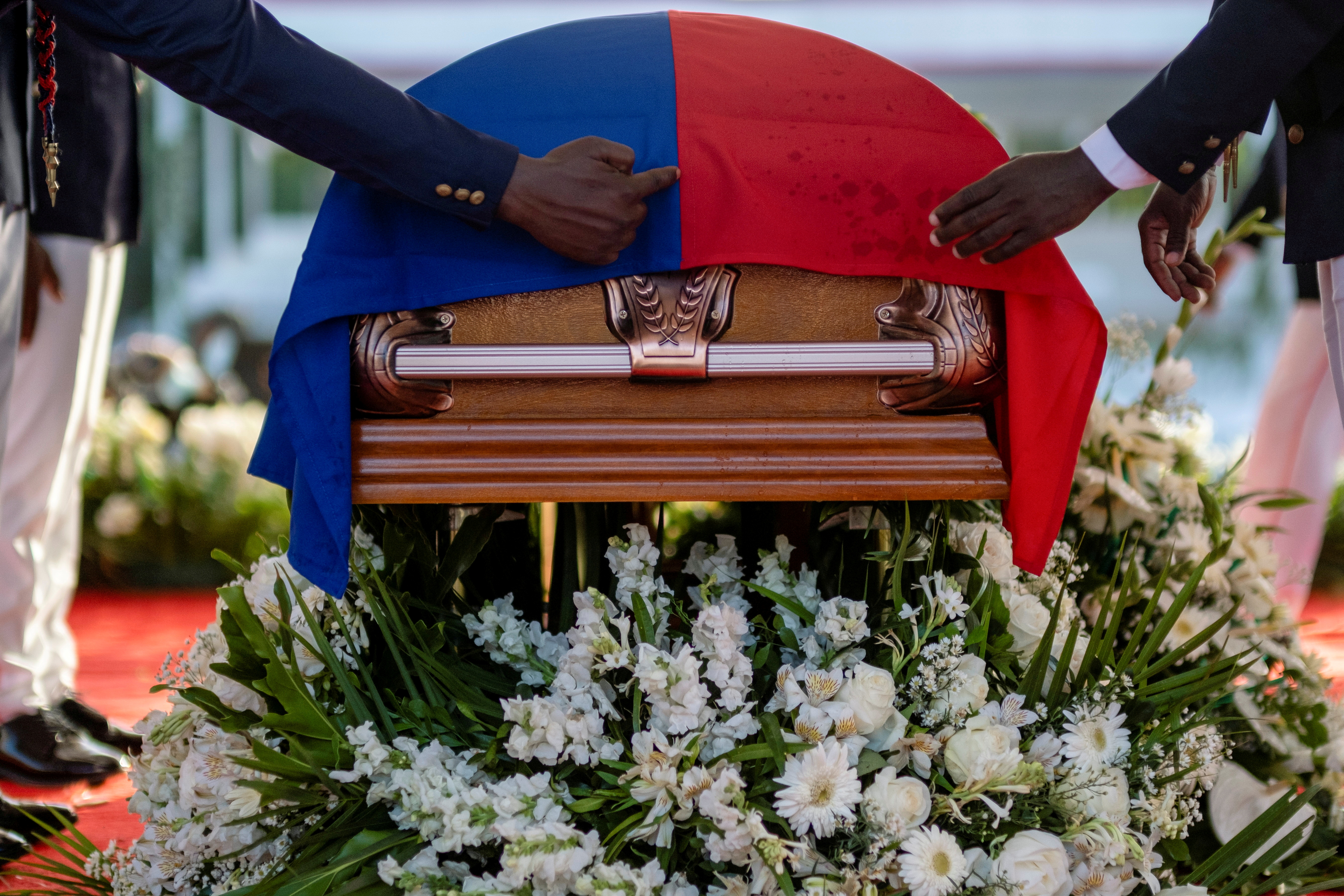 Presidential honor guards place a national flag over the coffin of late Haitian President Jovenel Moise, who was shot dead earlier this month, during the funeral at his family home in Cap-Haitien, Haiti, July 23, 2021. REUTERS/Ricardo Arduengo/File Photo