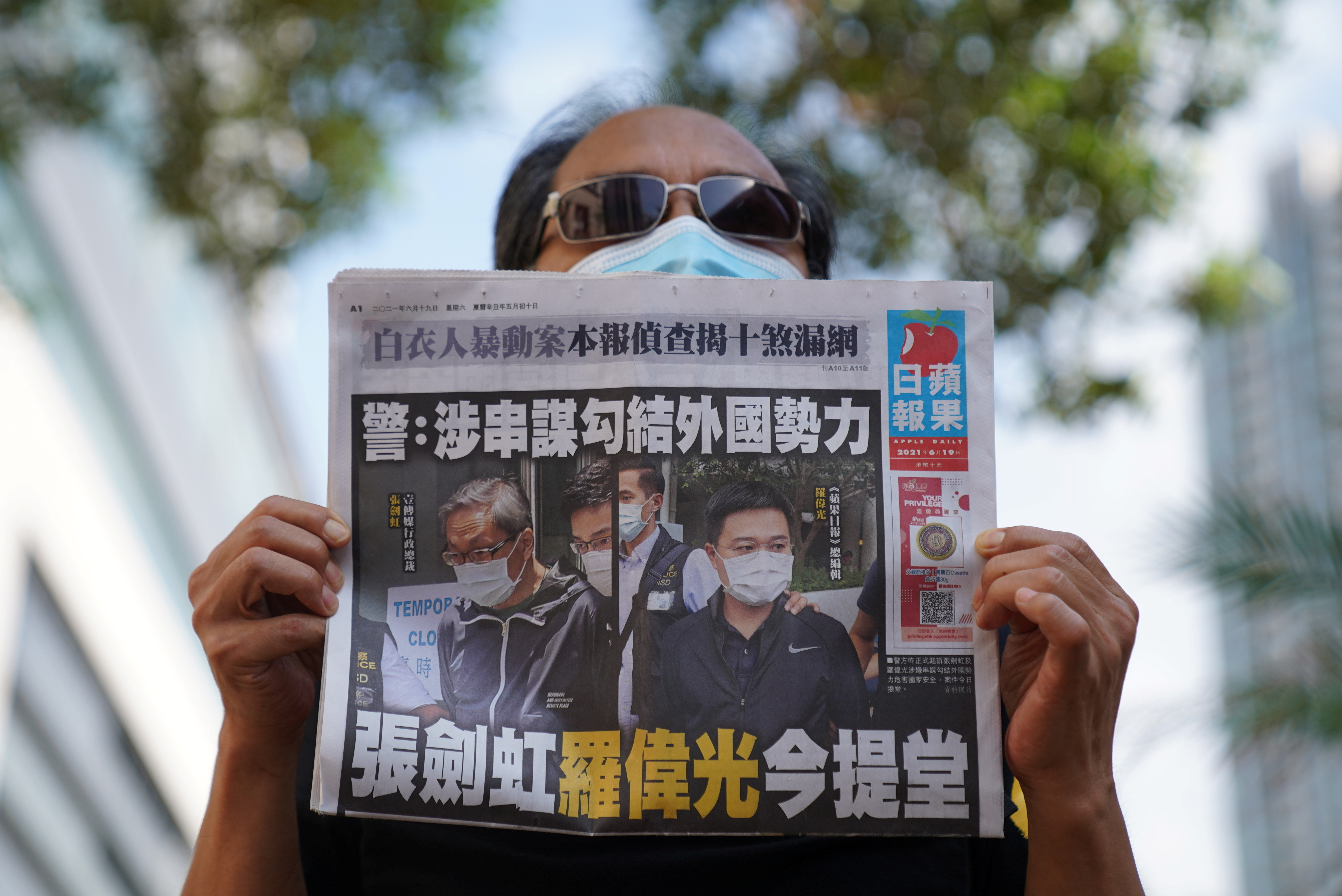 A supporter holds a copy of Apple Daily newspaper during a court hearing outside West Magistrates’ Courts, after police charge two executives of the pro-democracy Apple Daily newspaper over the national security law, in Hong Kong