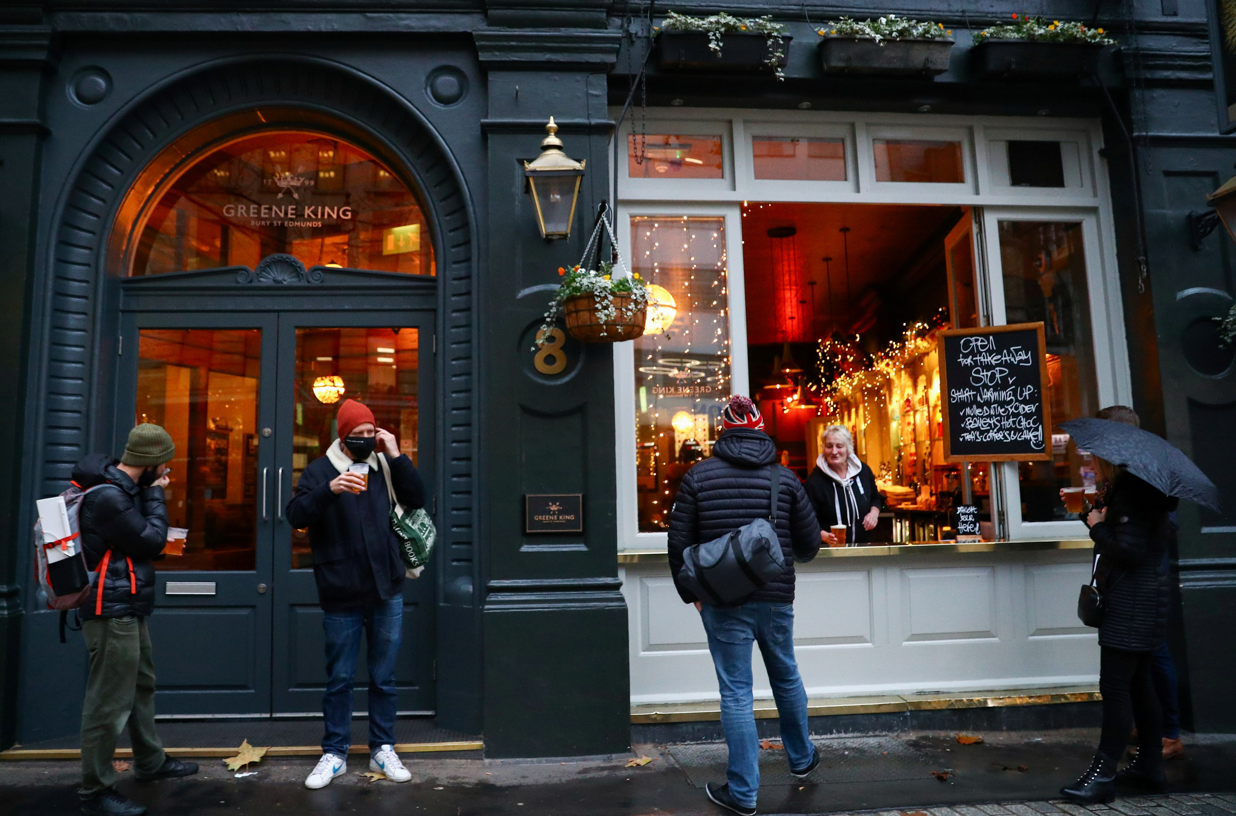 People drink outside a pub that is open for takeaway drinks in London