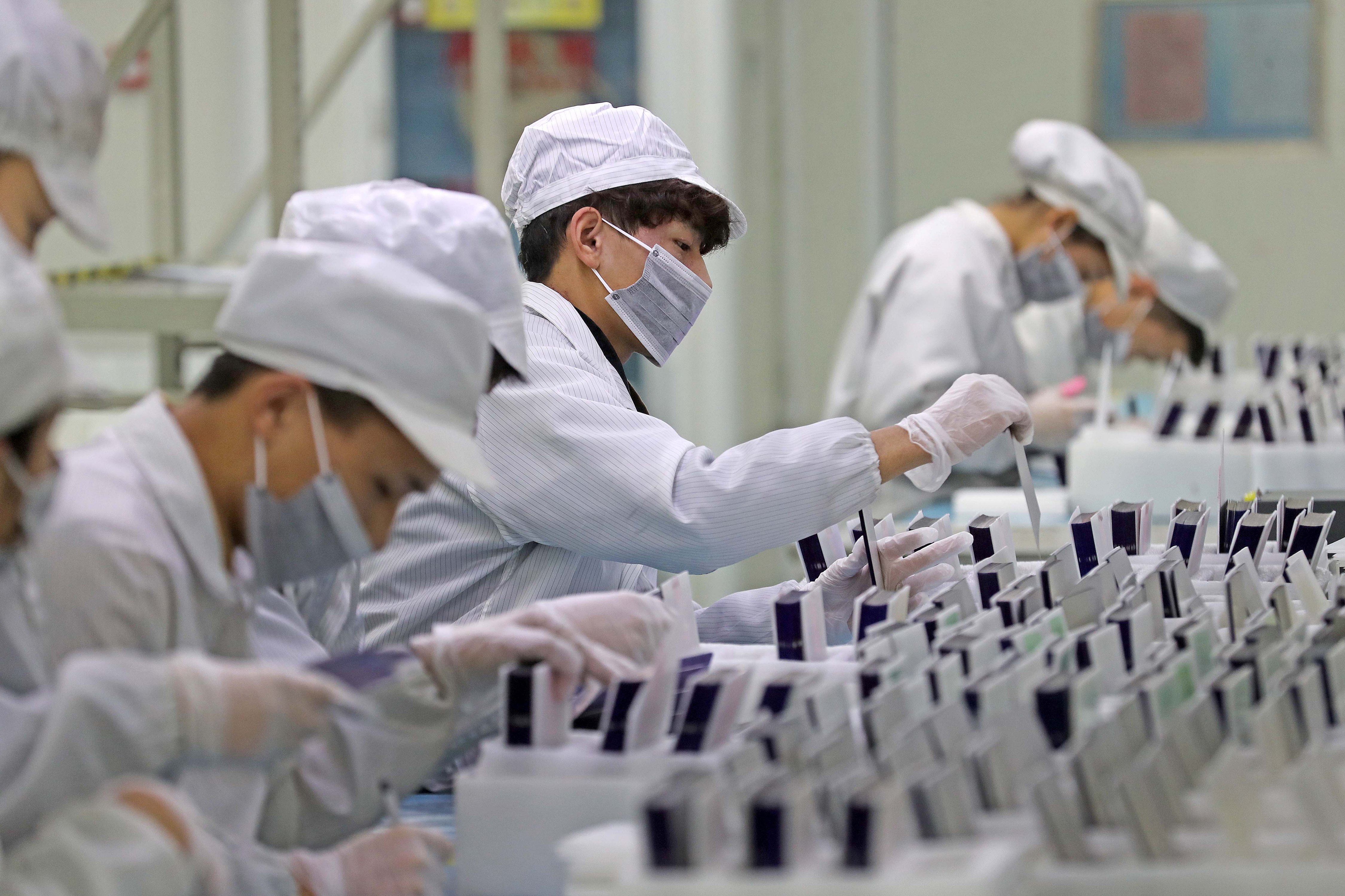 Workers are seen at a production line manufacturing solar photovoltaic components at a factory in Huzhou, Zhejiang