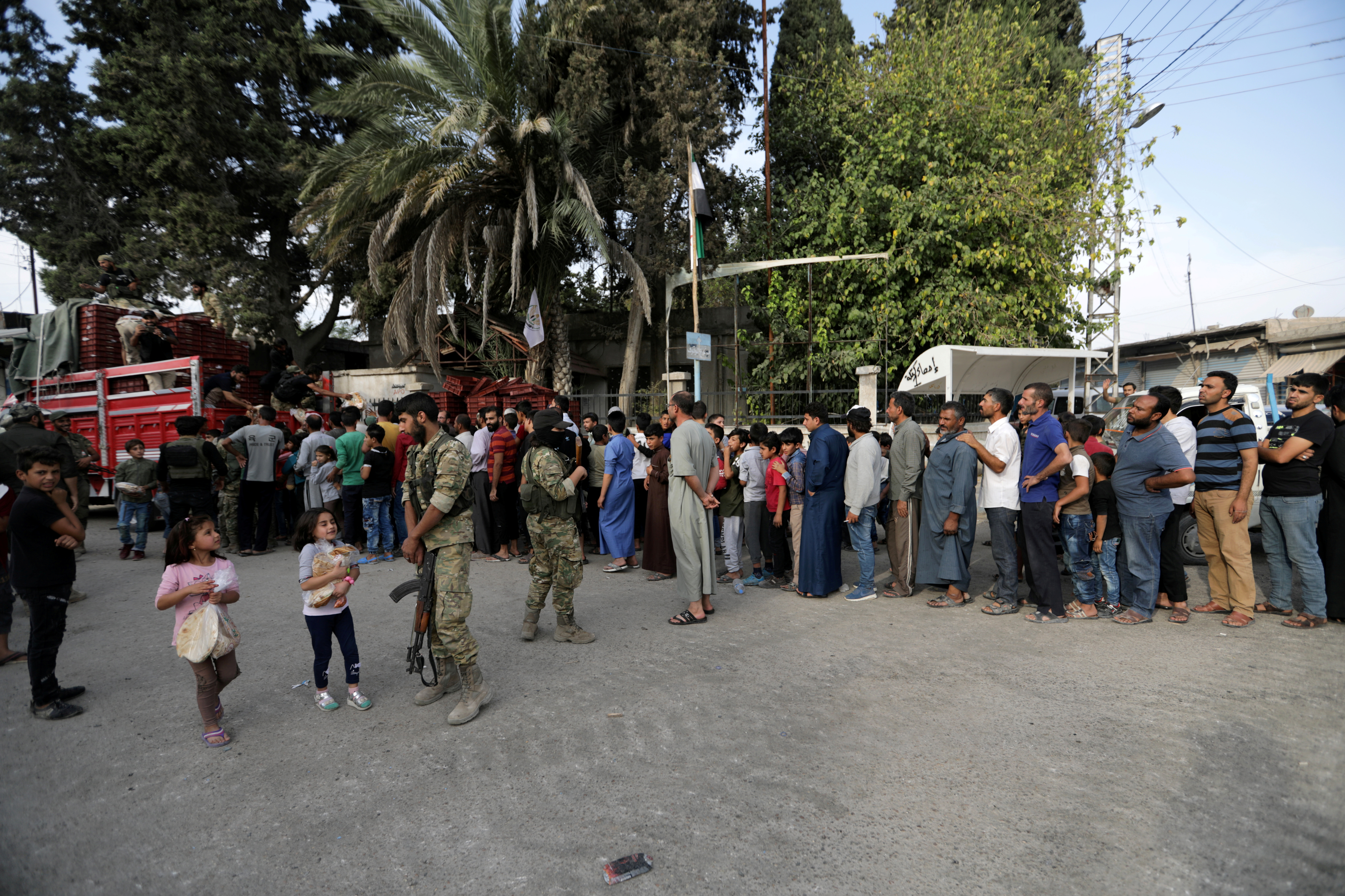 People stand in a queue to get bread in the border town of Tal Abyad, Syria, October 15, 2019. REUTERS/Khalil Ashawi