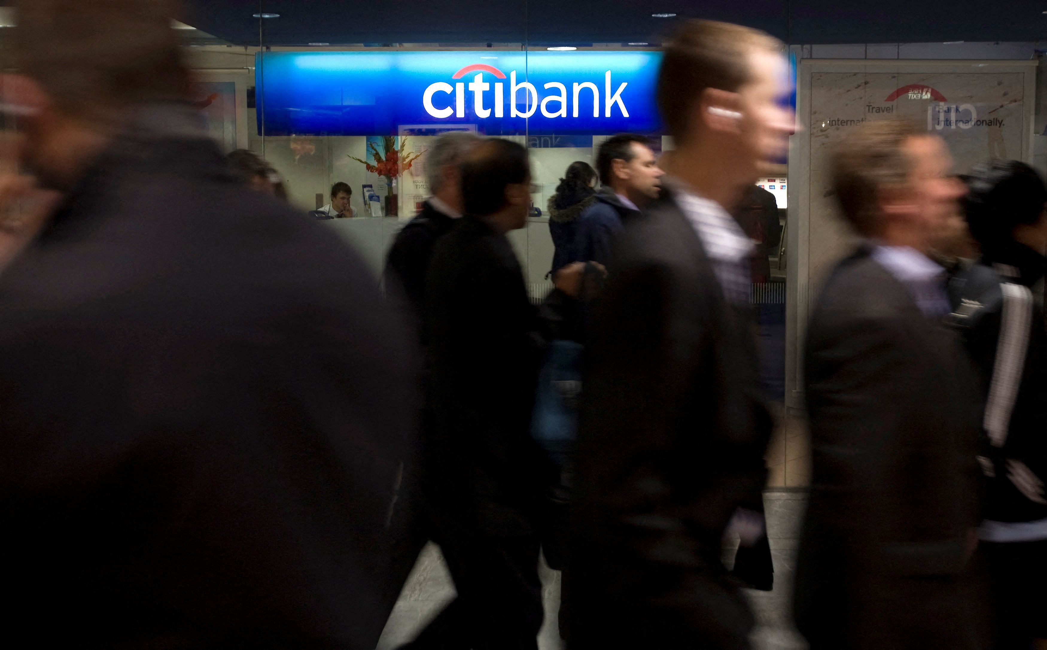 People walk past a Citibank branch during the lunchtime rush in London's financial district of Canary Wharf