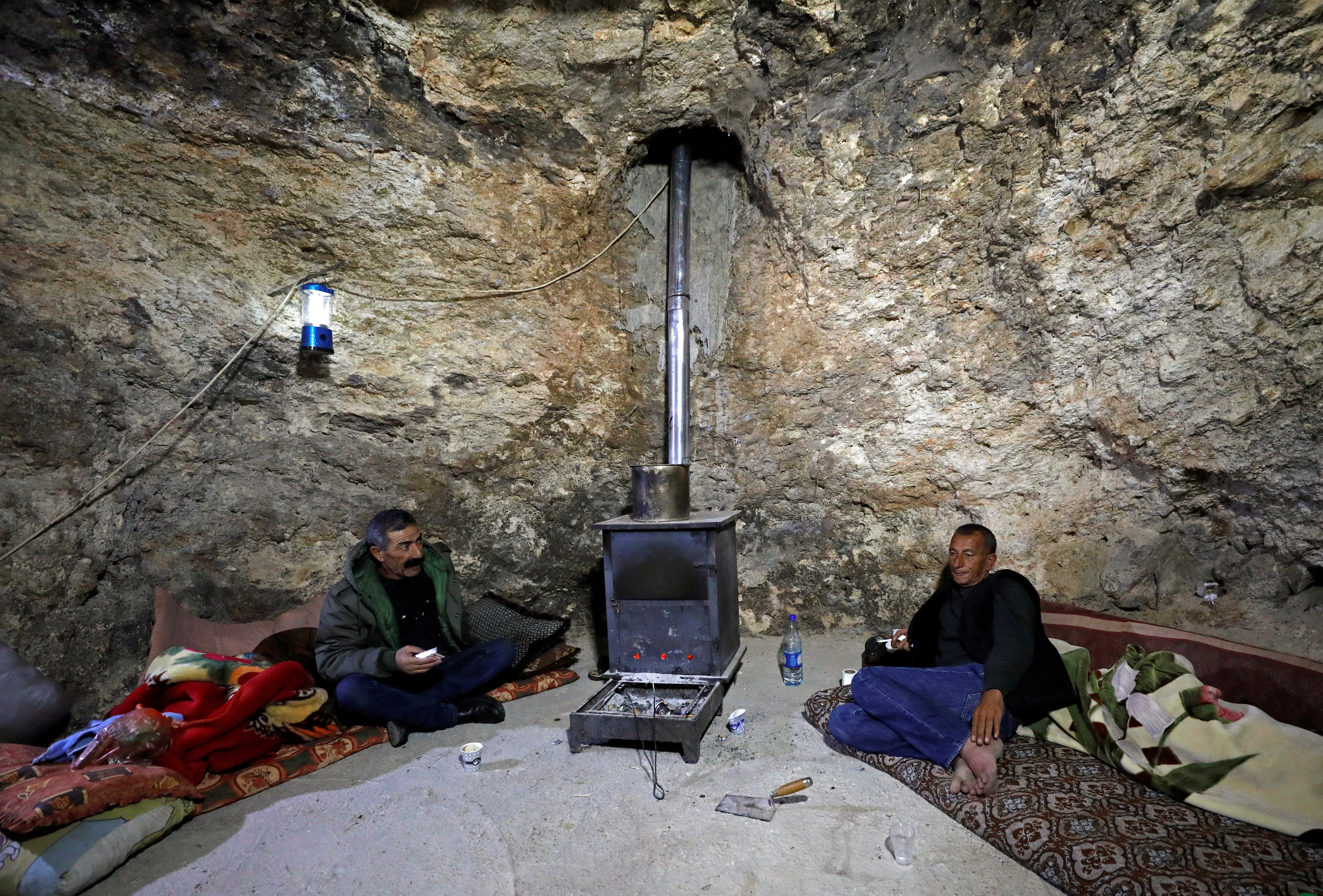 Two Palestinians sit in a hillside cave in Masafer Yatta near Hebron in the Israeli-occupied West Bank