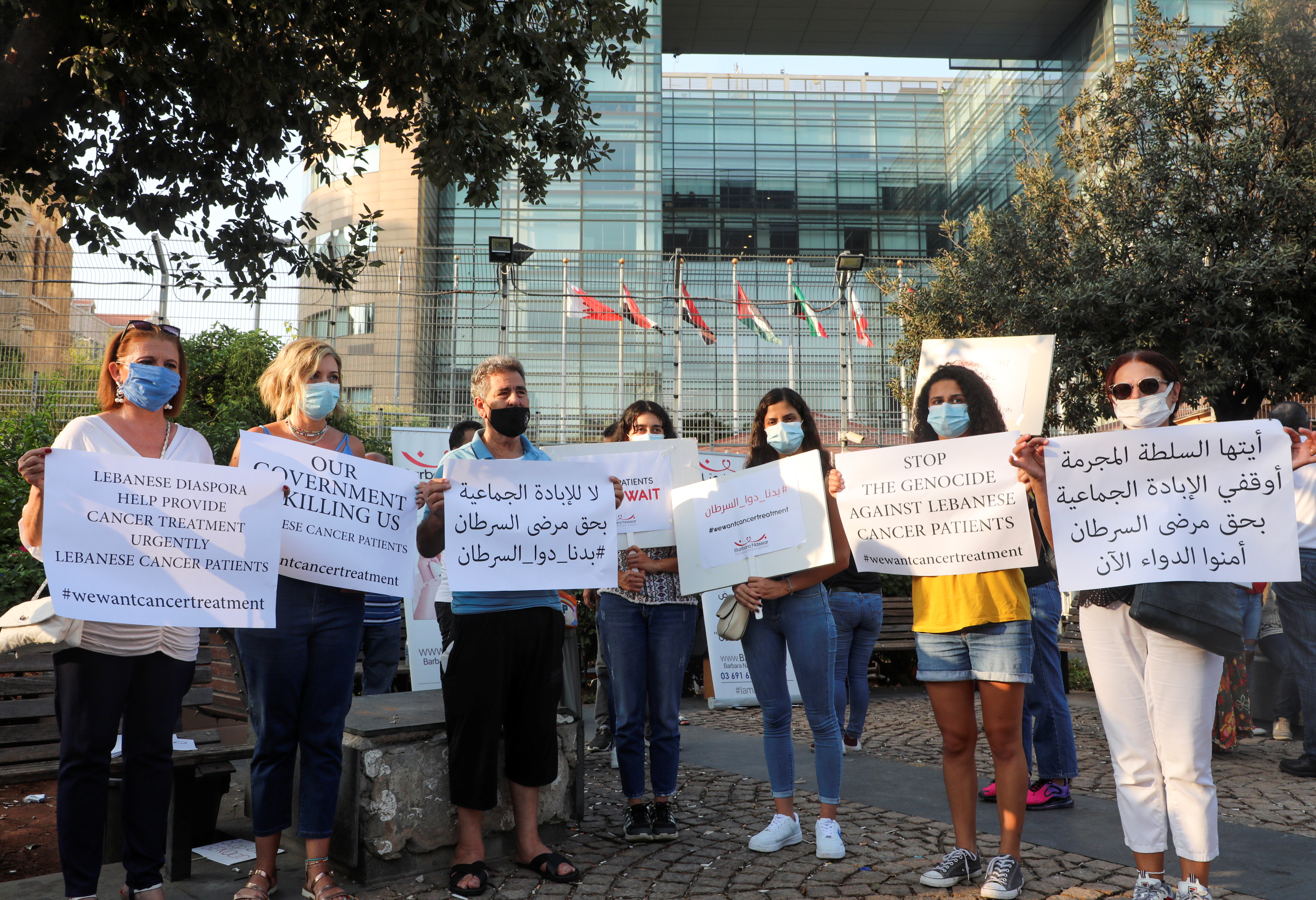 People hold signs during a sit-in demonstration as shortages of cancer medications spread, in front of the U.N. headquarters in Beirut
