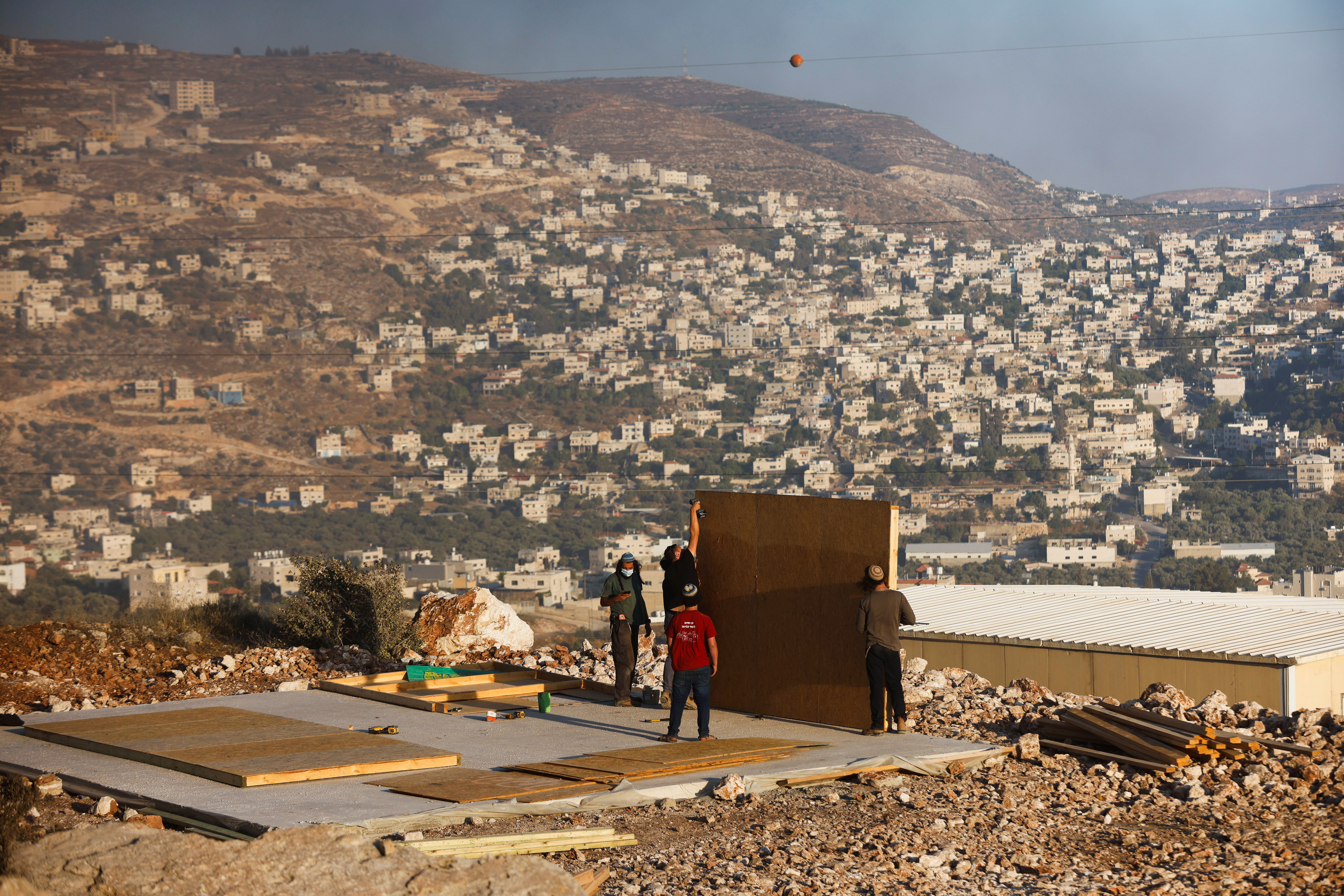 Jewish settlers youths construct a structure in Givat Eviatar, a new Israeli settler outpost, near the Palestinian village of Beita in the Israeli-occupied West Bank June 23, 2021. Picture taken June 23, 2021. REUTERS/Amir Cohen
