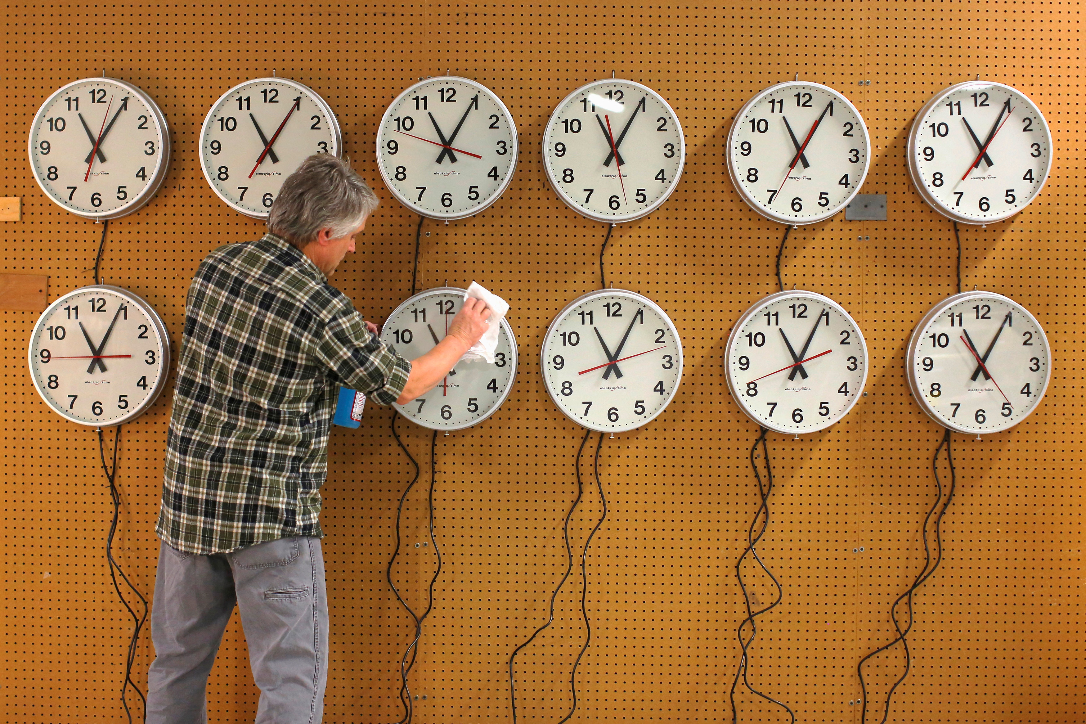 Scott Gow cleans the faces of wall clocks being tested at the Electric Time Company in Medfield, Massachusetts