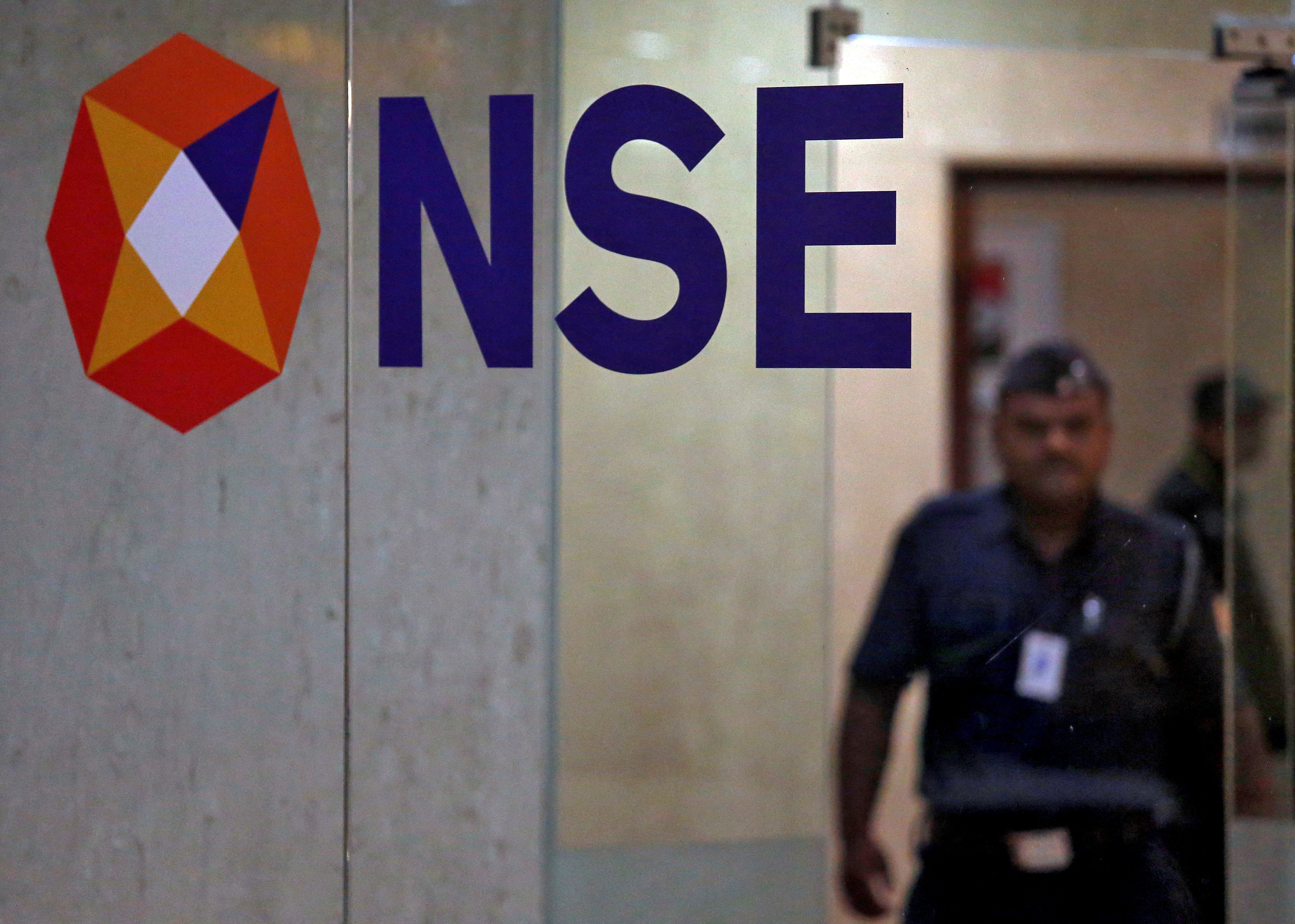 FILE PHOTO: A security guard walks past the logo of the National Stock Exchange inside its building in Mumbai