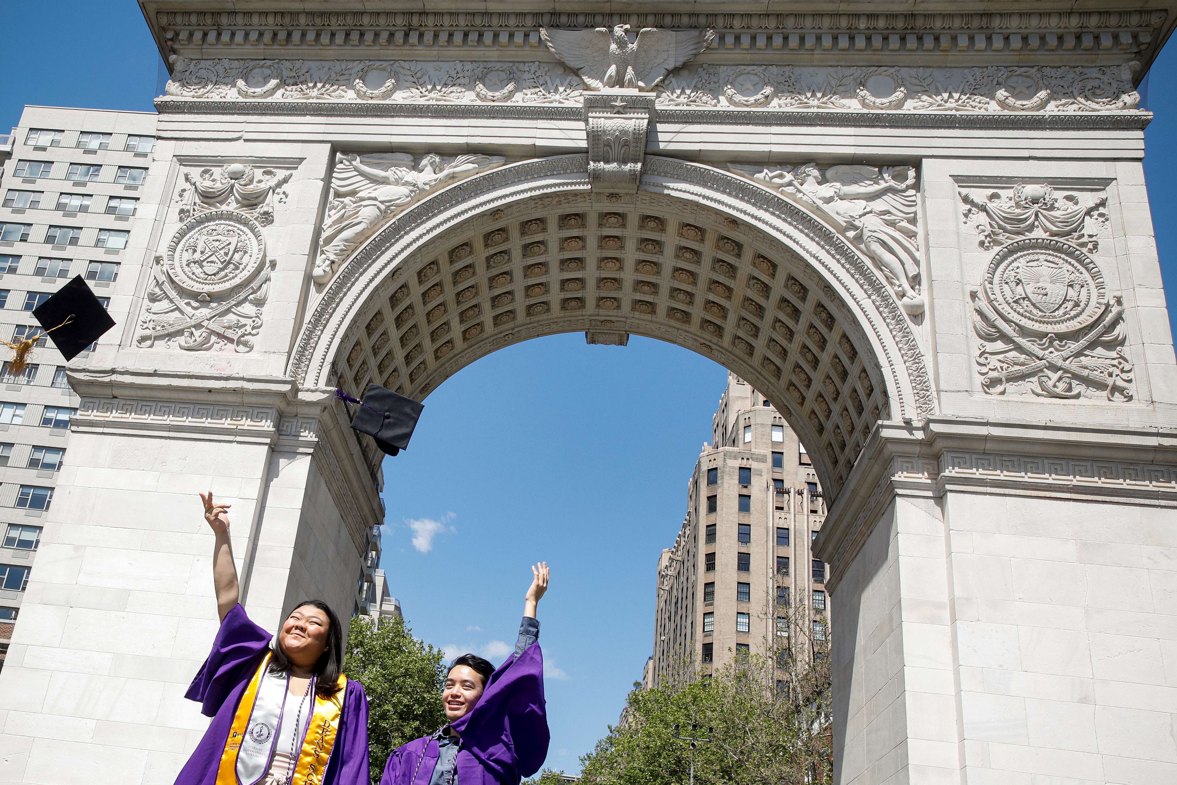 New York University graduates Rachel Kim and Melvin Nguyen pose together under the Washington Square Arch in Washington Square Park in New York