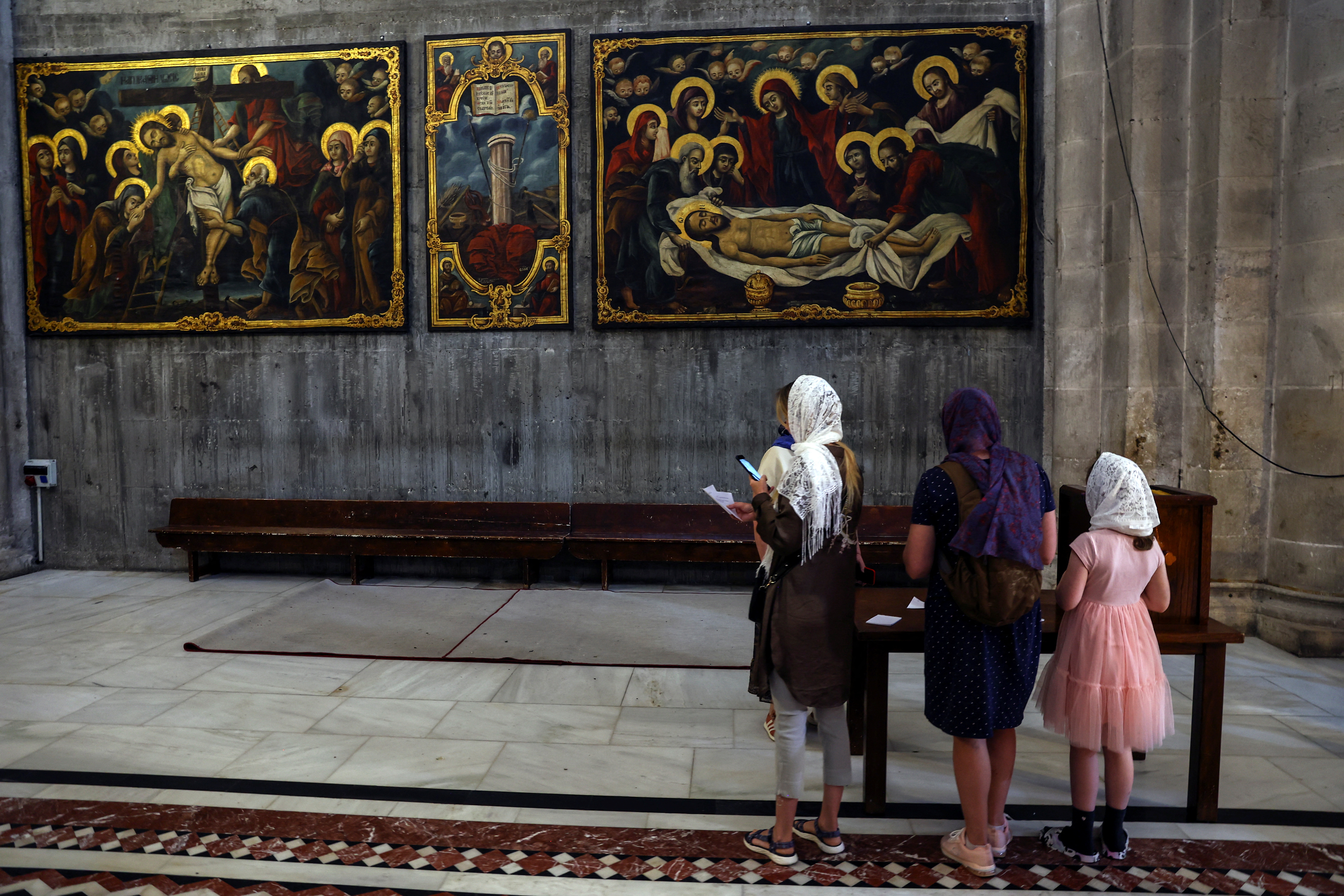 People view paintings during a visit to the Church of the Holy Sepulchre, in Jerusalem's Old City