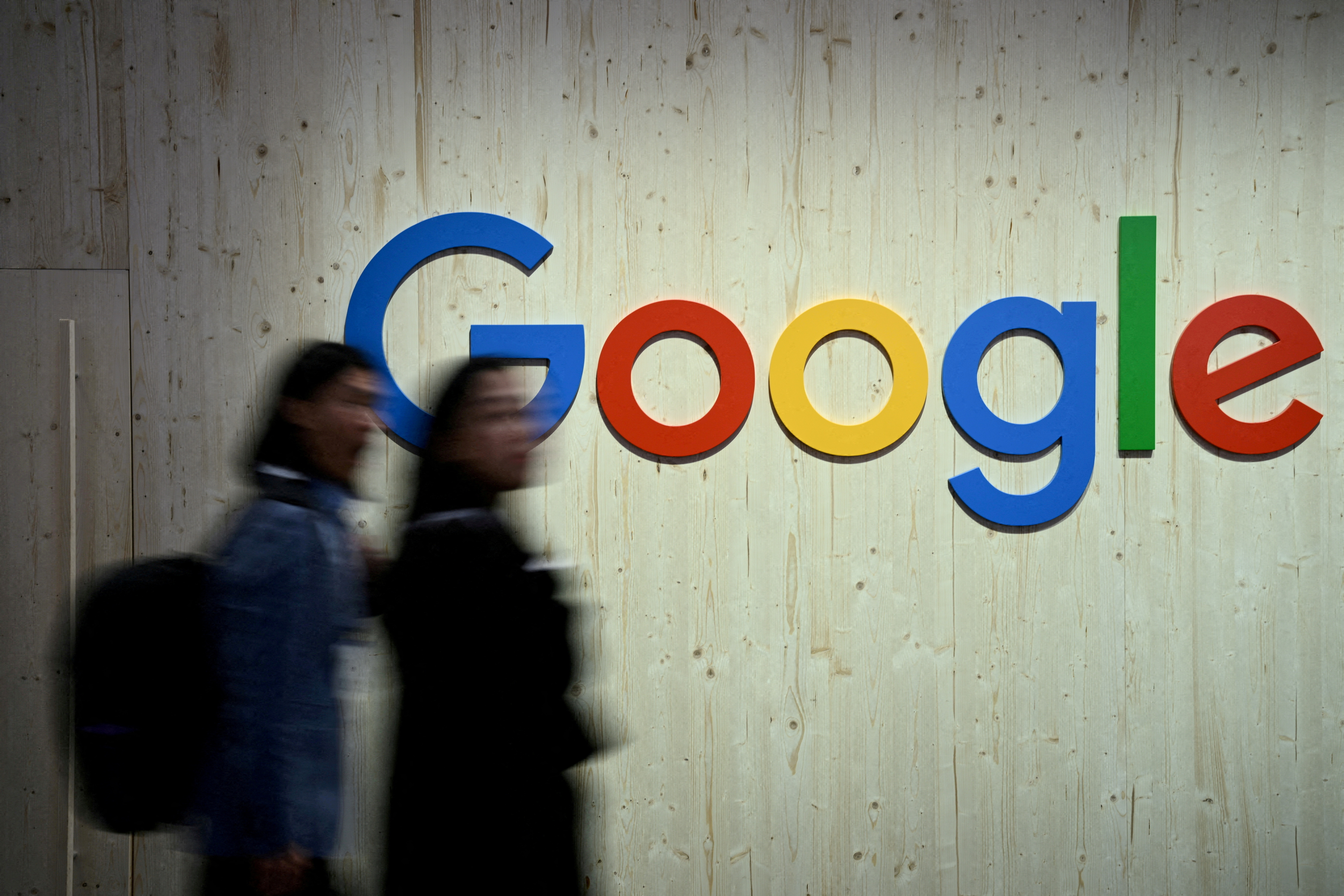 People walk next to a Google logo during a trade fair in Hannover Messe